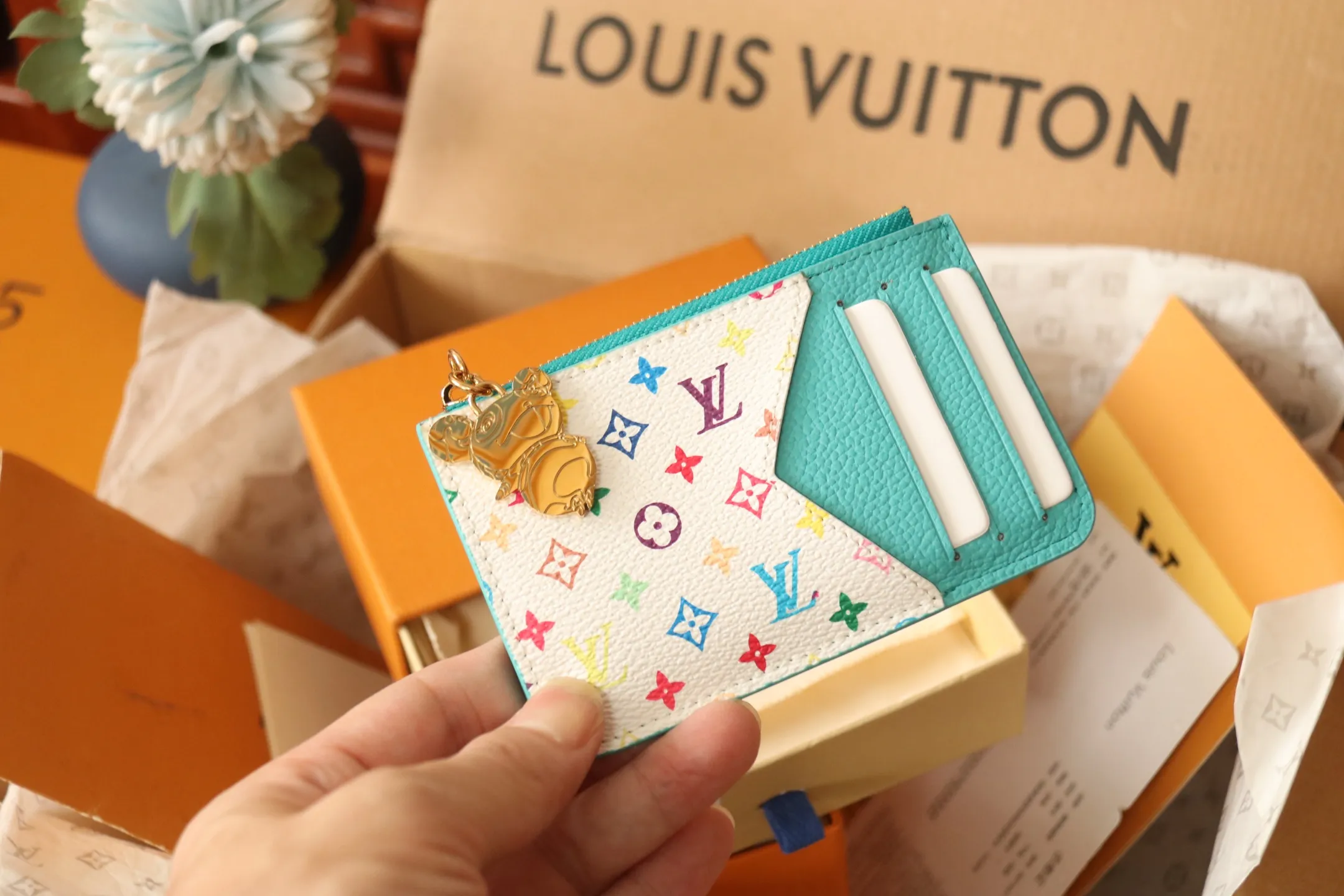 【LV x TM Romy Card Holder】 💎P400 m14155 Rose m14171 Blue m13800 Green "LV × TM Porto Kurt Romy" appears in the "Louis Vuitton × Takashi Murakami" series that unfolds in a variety of categories. It features functional and playful expressions with fresh tones inspired by the rainbow colors unique to Japanese artists. The whole piece is finished with Monogram Amplant leather that adds a casual personality, and the bright Monogram multi-color canvas in the flat pocket stands out. The coin pocket opens and closes with a gold zipper and features a panda pull to symbolize the season.  Dimensions: 12 x 8 x 0.8 cm