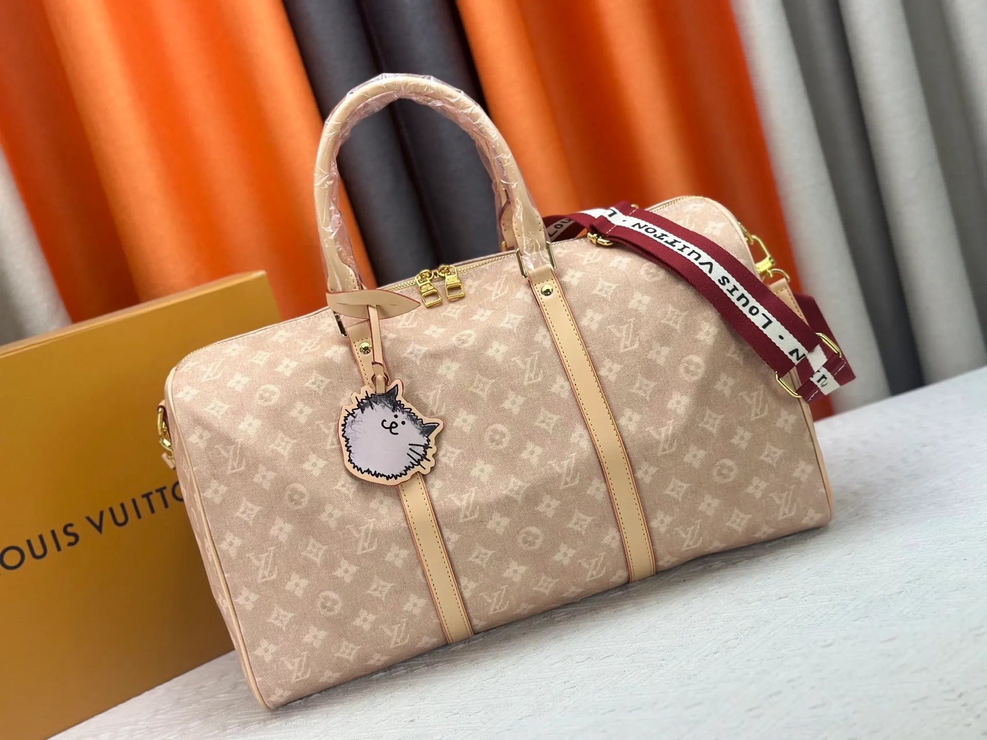 P360 M25787 This Keepall Bandouliere 45 travel bag is from the Travel With series presented by Louis Vuitton in collaboration with Grace Coddington. It uses Meowgram canvas to interpret the Monogram pattern in a playful reinvention, looking back to the hard suitcase inspiration of the 1900s. The cute cat-shaped branding adds smart touches, and the detachable and adjustable shoulder strap is embellished with the handwritten brand logo. Size: 45x27x20cm