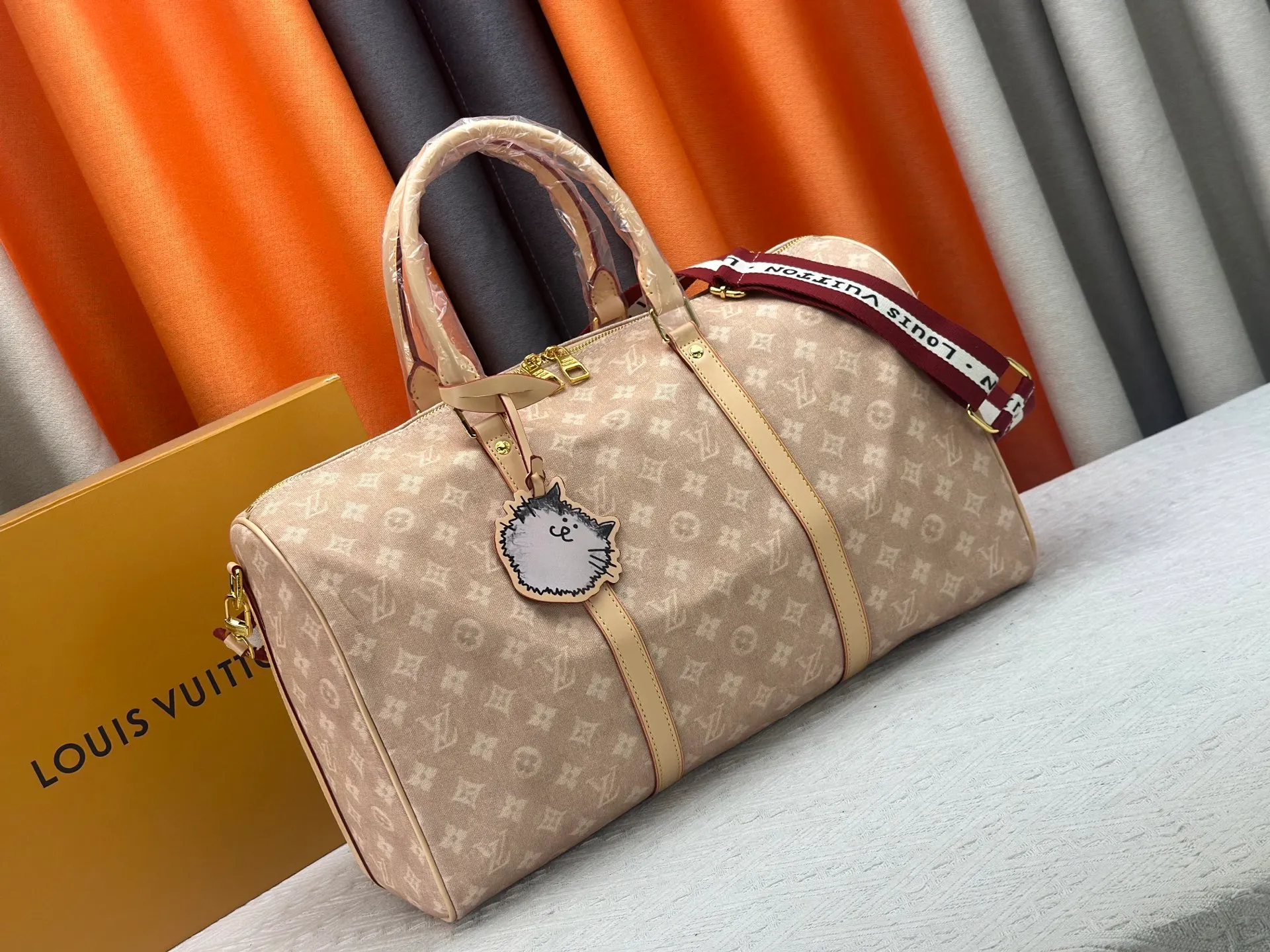 P360 M25787 This Keepall Bandouliere 45 travel bag is from the Travel With series presented by Louis Vuitton in collaboration with Grace Coddington. It uses Meowgram canvas to interpret the Monogram pattern in a playful reinvention, looking back to the hard suitcase inspiration of the 1900s. The cute cat-shaped branding adds smart touches, and the detachable and adjustable shoulder strap is embellished with the handwritten brand logo. Size: 45x27x20cm