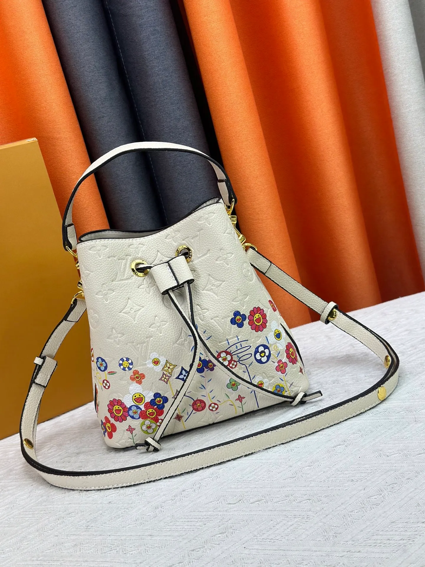 P240 M13676 M44021 This NeoNoe BB bucket bag comes from the Louis Vuitton × Murakami replica series, using Monogram Empreinte leather to convey a fresh breath and smart style. Murakami's signature Cherry Blossom pattern appears on the Monogram embossed surface, and the same floral element is transformed into a slide buckle to tighten the drawstring. Size: 20x20x13cm