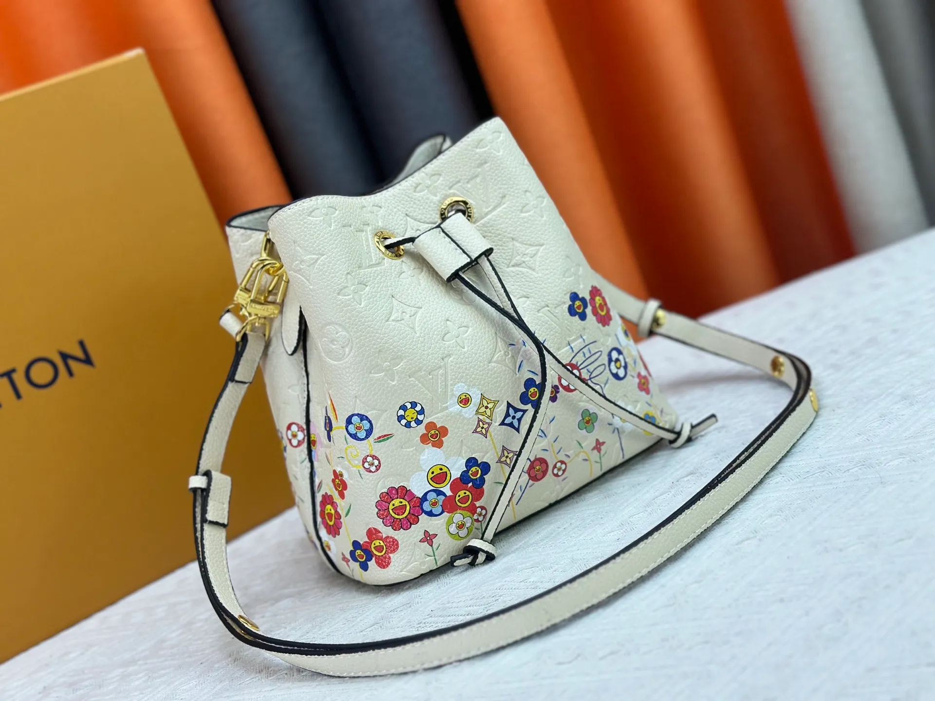 P240 M13676 M44021 This NeoNoe BB bucket bag comes from the Louis Vuitton × Murakami replica series, using Monogram Empreinte leather to convey a fresh breath and smart style. Murakami's signature Cherry Blossom pattern appears on the Monogram embossed surface, and the same floral element is transformed into a slide buckle to tighten the drawstring. Size: 20x20x13cm