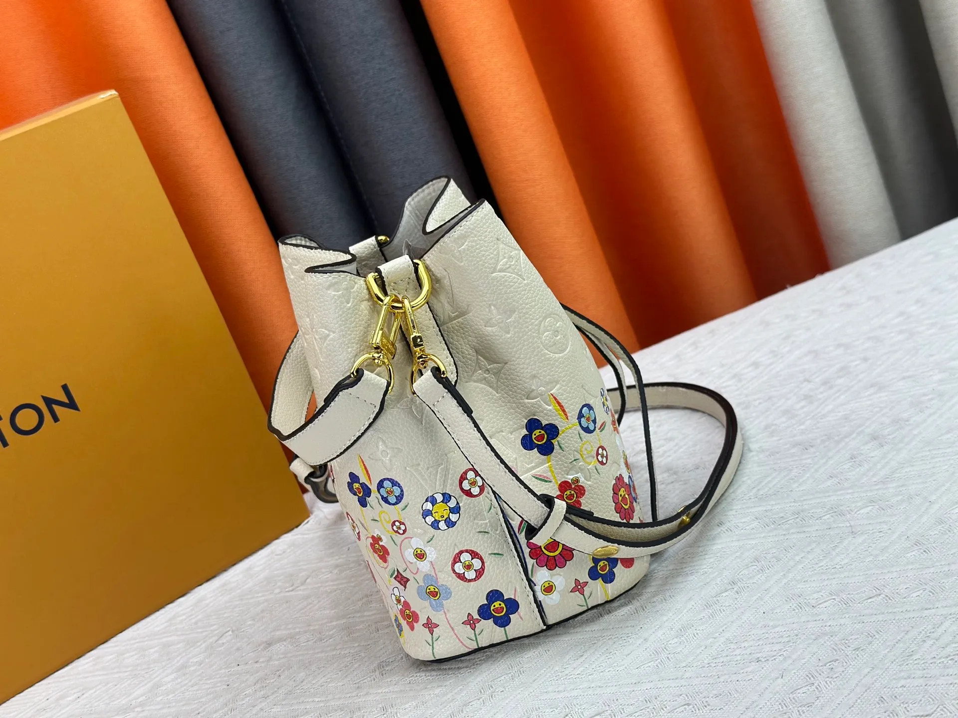 P240 M13676 M44021 This NeoNoe BB bucket bag comes from the Louis Vuitton × Murakami replica series, using Monogram Empreinte leather to convey a fresh breath and smart style. Murakami's signature Cherry Blossom pattern appears on the Monogram embossed surface, and the same floral element is transformed into a slide buckle to tighten the drawstring. Size: 20x20x13cm