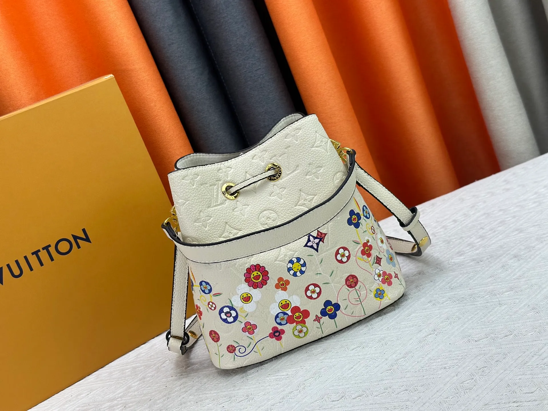 P240 M13676 M44021 This NeoNoe BB bucket bag comes from the Louis Vuitton × Murakami replica series, using Monogram Empreinte leather to convey a fresh breath and smart style. Murakami's signature Cherry Blossom pattern appears on the Monogram embossed surface, and the same floral element is transformed into a slide buckle to tighten the drawstring. Size: 20x20x13cm
