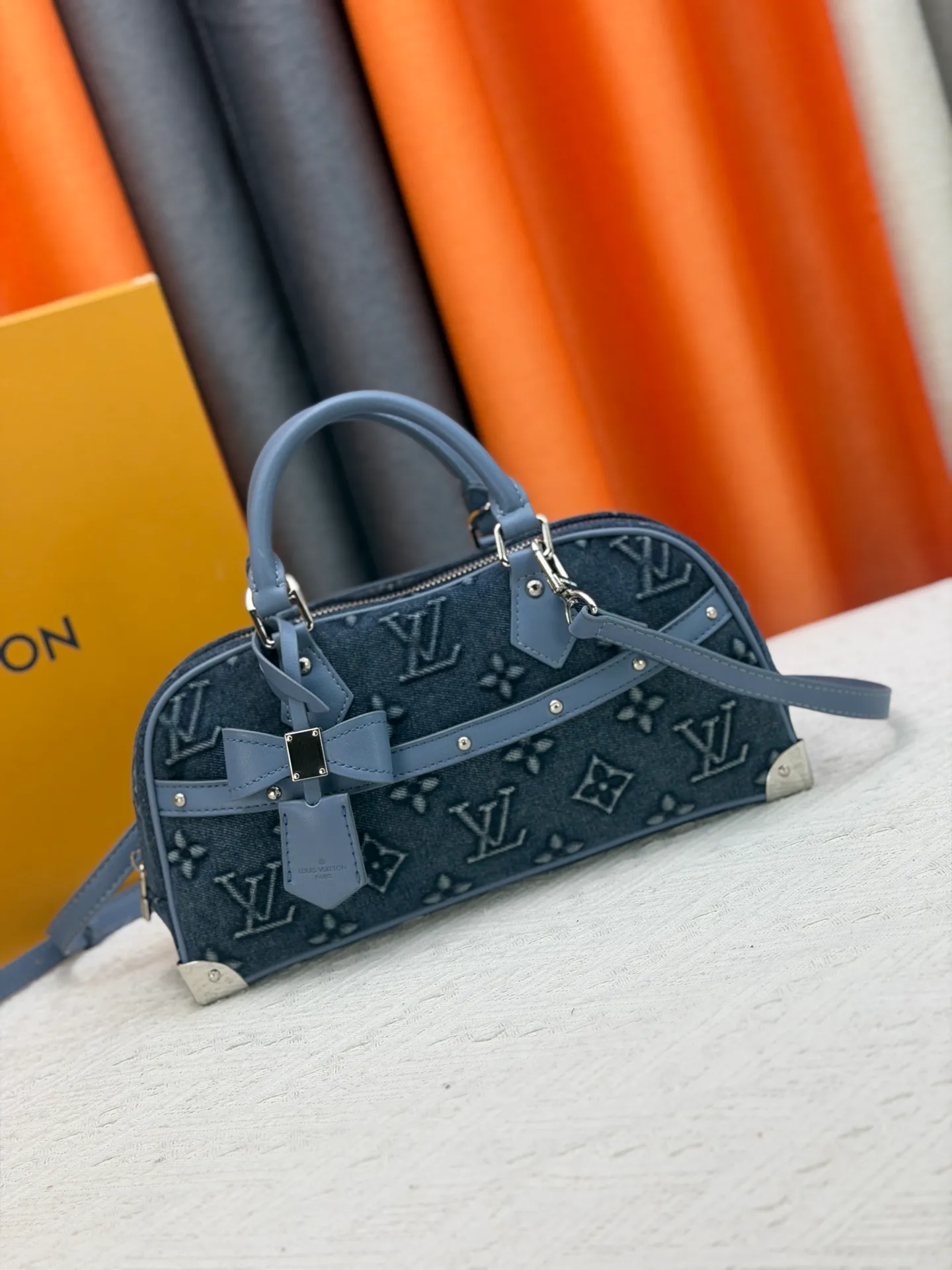 P360 M13084 Embossed Denim This Handbag East West handbag is from the Louis Vuitton x Takashi Murakami reissue series, using the artist's signature rainbow tones to trace the full-length Monogram pattern. Sleek horizontal construction lines the top handle, studded side straps, detachable and adjustable shoulder strap and LV x TM key holder, with cowhide leather details and sophisticated corners that nod to the brand's traditional luggage.  14 x 10 x 27 cm (H x W x L) Monogram coated canvas Cow leather trim Textile lining Metal hardware Zip closure Internal pocket Holds smartphone, keys, headphones and Zippy wallet Shoulder strap: removable, not adjustable Strap half-length: 44.0 cm Handle: Double handle