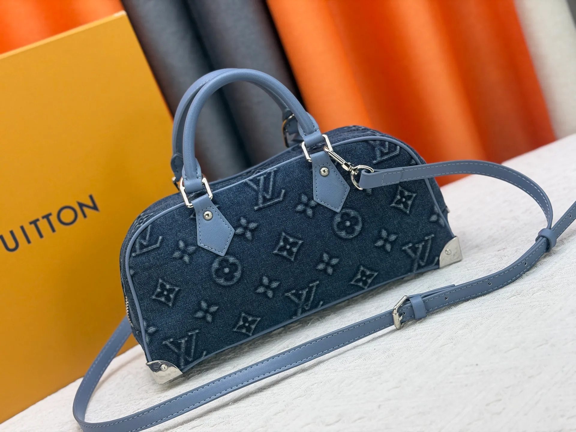 P360 M13084 Embossed Denim This Handbag East West handbag is from the Louis Vuitton x Takashi Murakami reissue series, using the artist's signature rainbow tones to trace the full-length Monogram pattern. Sleek horizontal construction lines the top handle, studded side straps, detachable and adjustable shoulder strap and LV x TM key holder, with cowhide leather details and sophisticated corners that nod to the brand's traditional luggage.  14 x 10 x 27 cm (H x W x L) Monogram coated canvas Cow leather trim Textile lining Metal hardware Zip closure Internal pocket Holds smartphone, keys, headphones and Zippy wallet Shoulder strap: removable, not adjustable Strap half-length: 44.0 cm Handle: Double handle