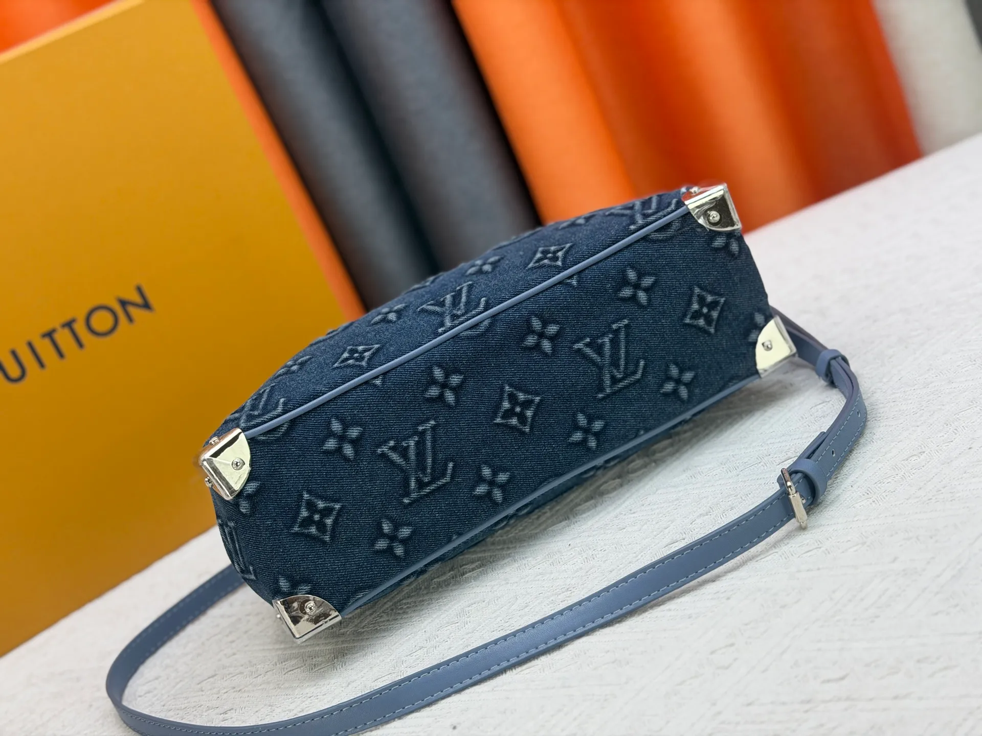 P360 M13084 Embossed Denim This Handbag East West handbag is from the Louis Vuitton x Takashi Murakami reissue series, using the artist's signature rainbow tones to trace the full-length Monogram pattern. Sleek horizontal construction lines the top handle, studded side straps, detachable and adjustable shoulder strap and LV x TM key holder, with cowhide leather details and sophisticated corners that nod to the brand's traditional luggage.  14 x 10 x 27 cm (H x W x L) Monogram coated canvas Cow leather trim Textile lining Metal hardware Zip closure Internal pocket Holds smartphone, keys, headphones and Zippy wallet Shoulder strap: removable, not adjustable Strap half-length: 44.0 cm Handle: Double handle