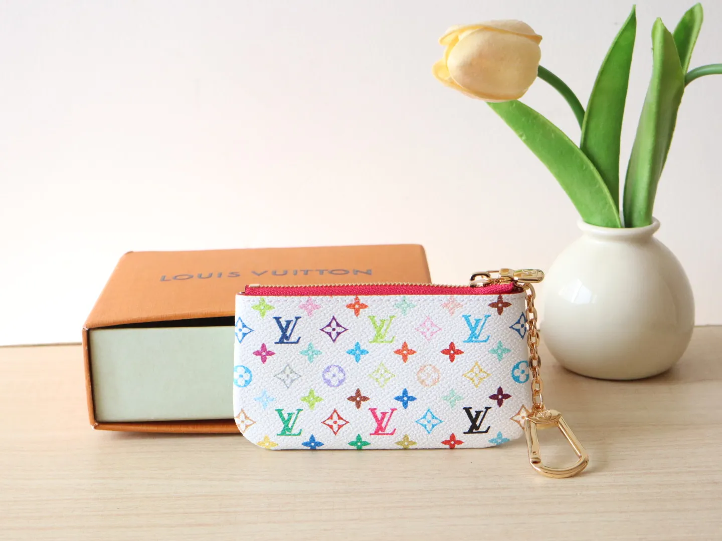 13664 Tricolor Coin Purse🌟P84 This replica Louis Vuitton x Murakami series key coin purse is colorful and made of coated canvas. The vibrant iconic Monogram pattern reinterprets the brand logo with the theme of Japanese artist Takashi Murakami in rainbow tones. The key coin purse has a silver zipper and is equipped with a chain strap and hook buckle to store keys securely. 12 x 7 x 1.5 cm (length x height x width)