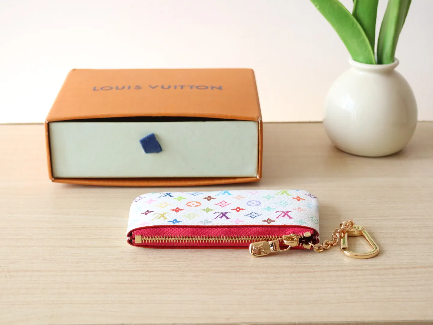 13664 Tricolor Coin Purse🌟P84 This replica Louis Vuitton x Murakami series key coin purse is colorful and made of coated canvas. The vibrant iconic Monogram pattern reinterprets the brand logo with the theme of Japanese artist Takashi Murakami in rainbow tones. The key coin purse has a silver zipper and is equipped with a chain strap and hook buckle to store keys securely. 12 x 7 x 1.5 cm (length x height x width)