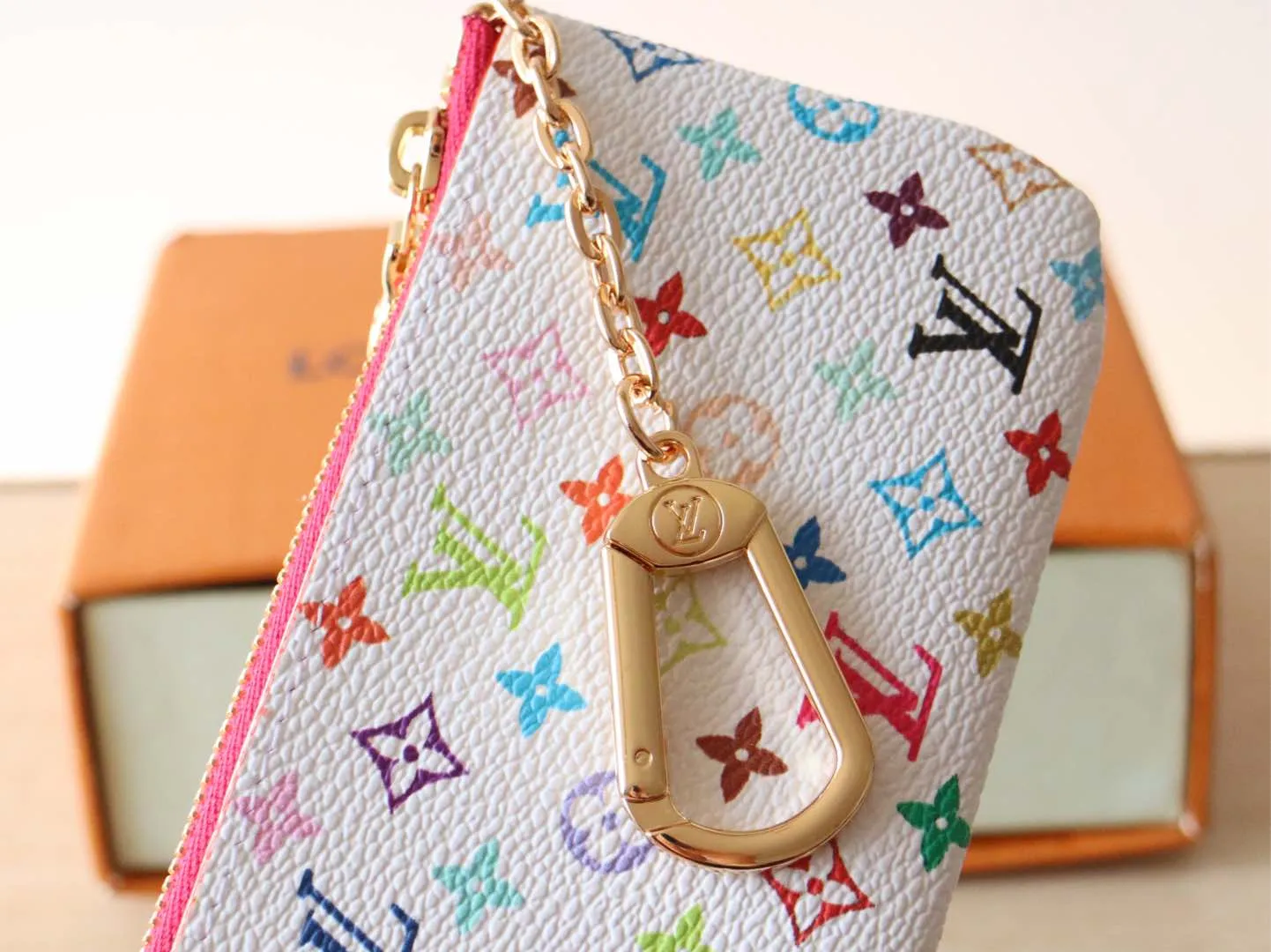 13664 Tricolor Coin Purse🌟P84 This replica Louis Vuitton x Murakami series key coin purse is colorful and made of coated canvas. The vibrant iconic Monogram pattern reinterprets the brand logo with the theme of Japanese artist Takashi Murakami in rainbow tones. The key coin purse has a silver zipper and is equipped with a chain strap and hook buckle to store keys securely. 12 x 7 x 1.5 cm (length x height x width)
