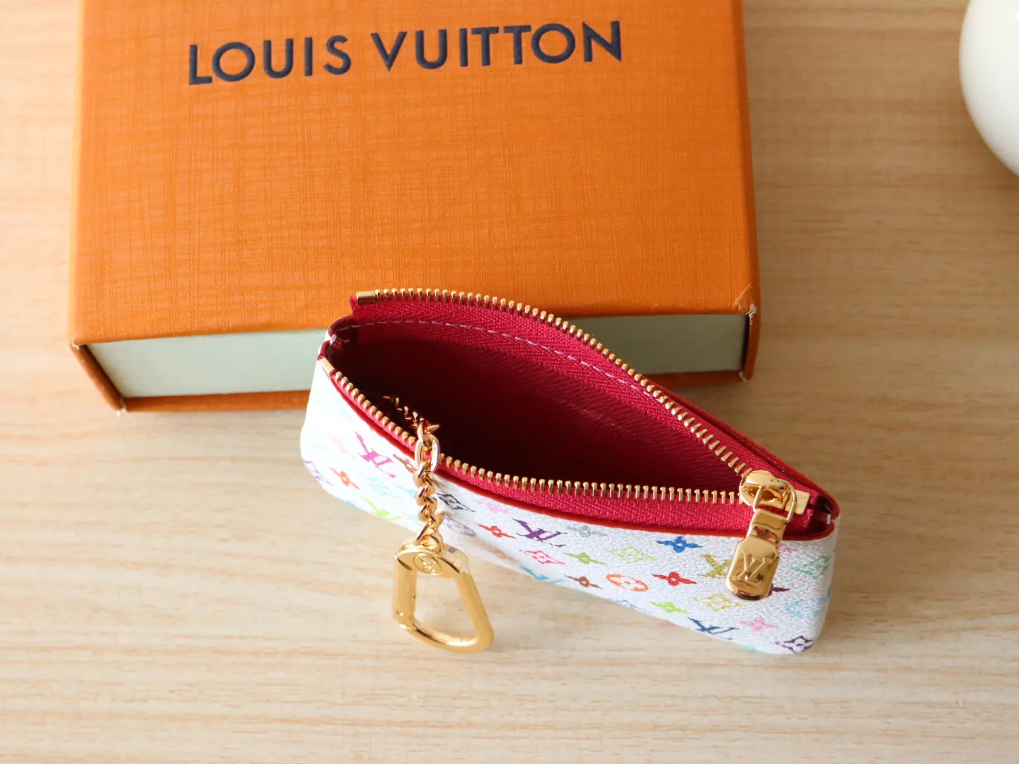 13664 Tricolor Coin Purse🌟P84 This replica Louis Vuitton x Murakami series key coin purse is colorful and made of coated canvas. The vibrant iconic Monogram pattern reinterprets the brand logo with the theme of Japanese artist Takashi Murakami in rainbow tones. The key coin purse has a silver zipper and is equipped with a chain strap and hook buckle to store keys securely. 12 x 7 x 1.5 cm (length x height x width)