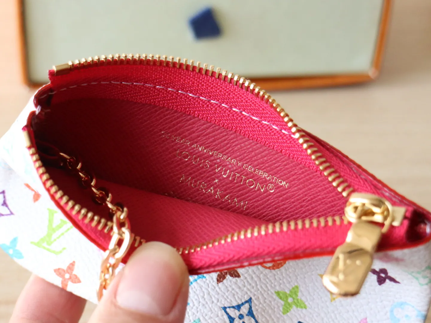 13664 Tricolor Coin Purse🌟P84 This replica Louis Vuitton x Murakami series key coin purse is colorful and made of coated canvas. The vibrant iconic Monogram pattern reinterprets the brand logo with the theme of Japanese artist Takashi Murakami in rainbow tones. The key coin purse has a silver zipper and is equipped with a chain strap and hook buckle to store keys securely. 12 x 7 x 1.5 cm (length x height x width)