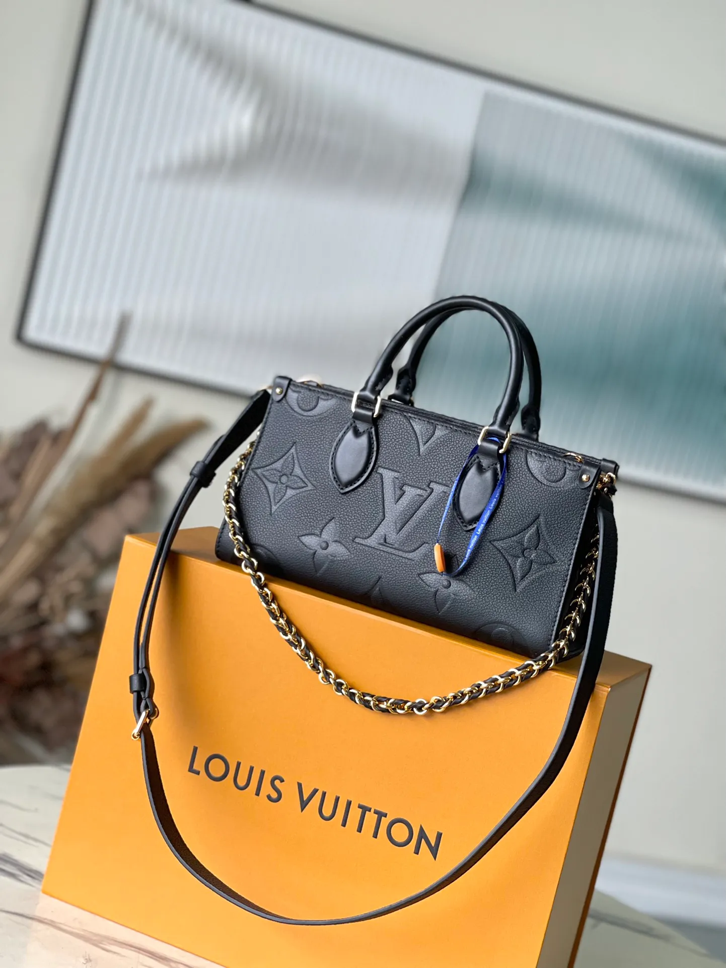 💰1060 (top-grain leather) top original M23640 black This OnTheGo East West handbag introduces the OnTheGo small tote bag design. It uses Monogram Empreinte leather to reinterpret East West's ample configuration. Giant Monogram is embossed on the leather body. The neat inner layer can store daily necessities. The top handle and detachable leather chain shoulder strap allow for multiple carrying methods. Size: 25x13x10cm