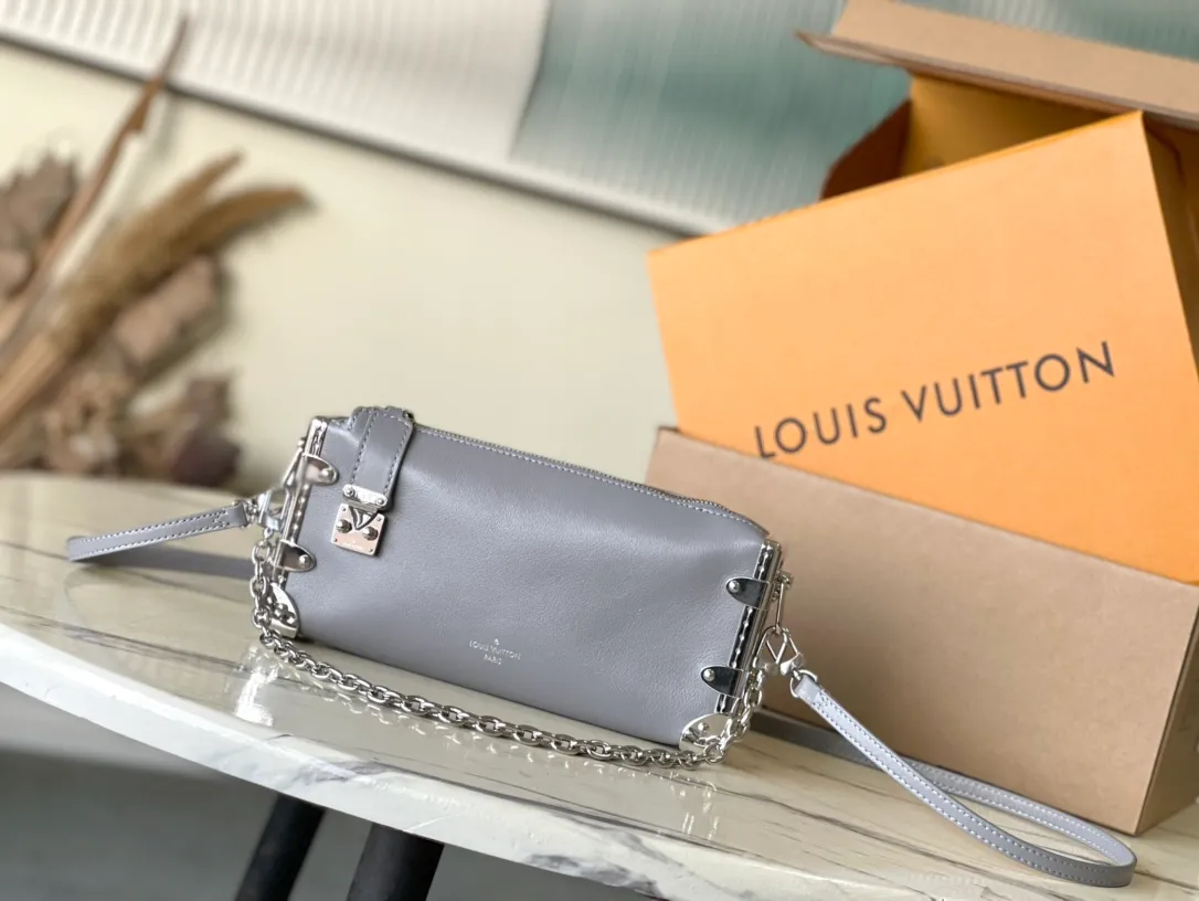 💰1420 (first-grain leather) Top-quality original order M12596 This Slim Trunk handbag draws inspiration from Louis Vuitton’s traditional hard trunk. The soft cow leather is integrated with rivet frames and metal S-lock locks, highlighting the avant-garde rock style. The shiny chain and adjustable leather shoulder strap are both detachable, providing a variety of carrying options. Dimensions: 23 × 12 × 4 cm