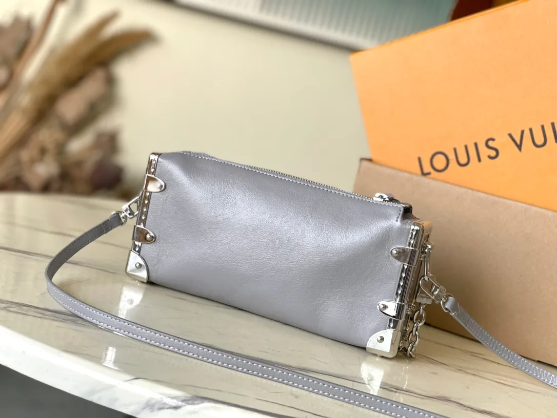 💰1420 (first-grain leather) Top-quality original order M12596 This Slim Trunk handbag draws inspiration from Louis Vuitton’s traditional hard trunk. The soft cow leather is integrated with rivet frames and metal S-lock locks, highlighting the avant-garde rock style. The shiny chain and adjustable leather shoulder strap are both detachable, providing a variety of carrying options. Dimensions: 23 × 12 × 4 cm