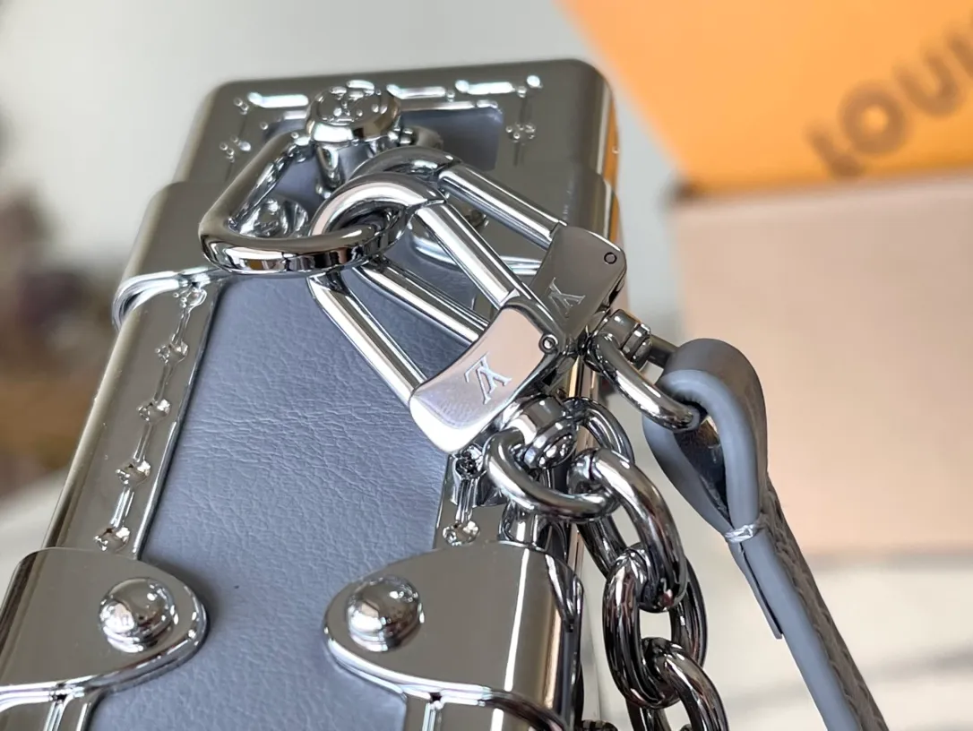 💰1420 (first-grain leather) Top-quality original order M12596 This Slim Trunk handbag draws inspiration from Louis Vuitton’s traditional hard trunk. The soft cow leather is integrated with rivet frames and metal S-lock locks, highlighting the avant-garde rock style. The shiny chain and adjustable leather shoulder strap are both detachable, providing a variety of carrying options. Dimensions: 23 × 12 × 4 cm