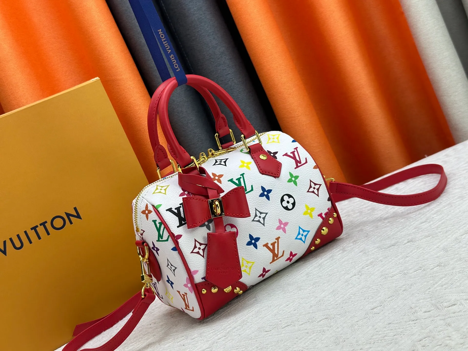 P260 upgraded original M58953 M46234 M46222 Speedy Bandoulière 20 handbag is made of soft coated canvas, and the full-length Monogram pattern is traced in colorful rainbow tones, highlighting the smart style of the Louis Vuitton x Murakami reissue series. The Toron handle and detachable shoulder strap are constructed of cow leather, the metal corners recall classic luggage elements, and the bow-shaped key bag and padlock add brand touches. Dimensions: 20.5 x 13.5 x 12.0 cm (length x height x width)