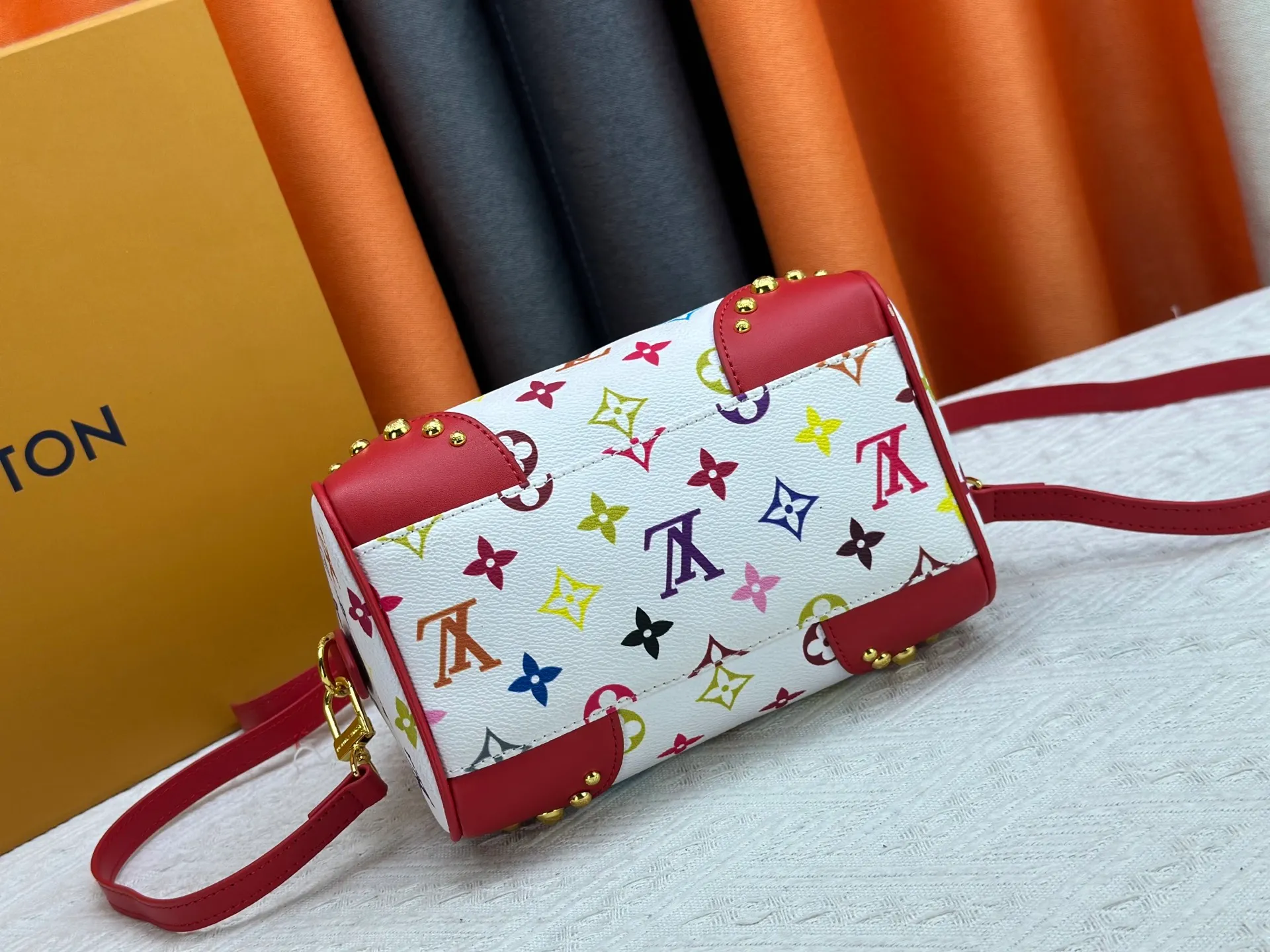P260 upgraded original M58953 M46234 M46222 Speedy Bandoulière 20 handbag is made of soft coated canvas, and the full-length Monogram pattern is traced in colorful rainbow tones, highlighting the smart style of the Louis Vuitton x Murakami reissue series. The Toron handle and detachable shoulder strap are constructed of cow leather, the metal corners recall classic luggage elements, and the bow-shaped key bag and padlock add brand touches. Dimensions: 20.5 x 13.5 x 12.0 cm (length x height x width)