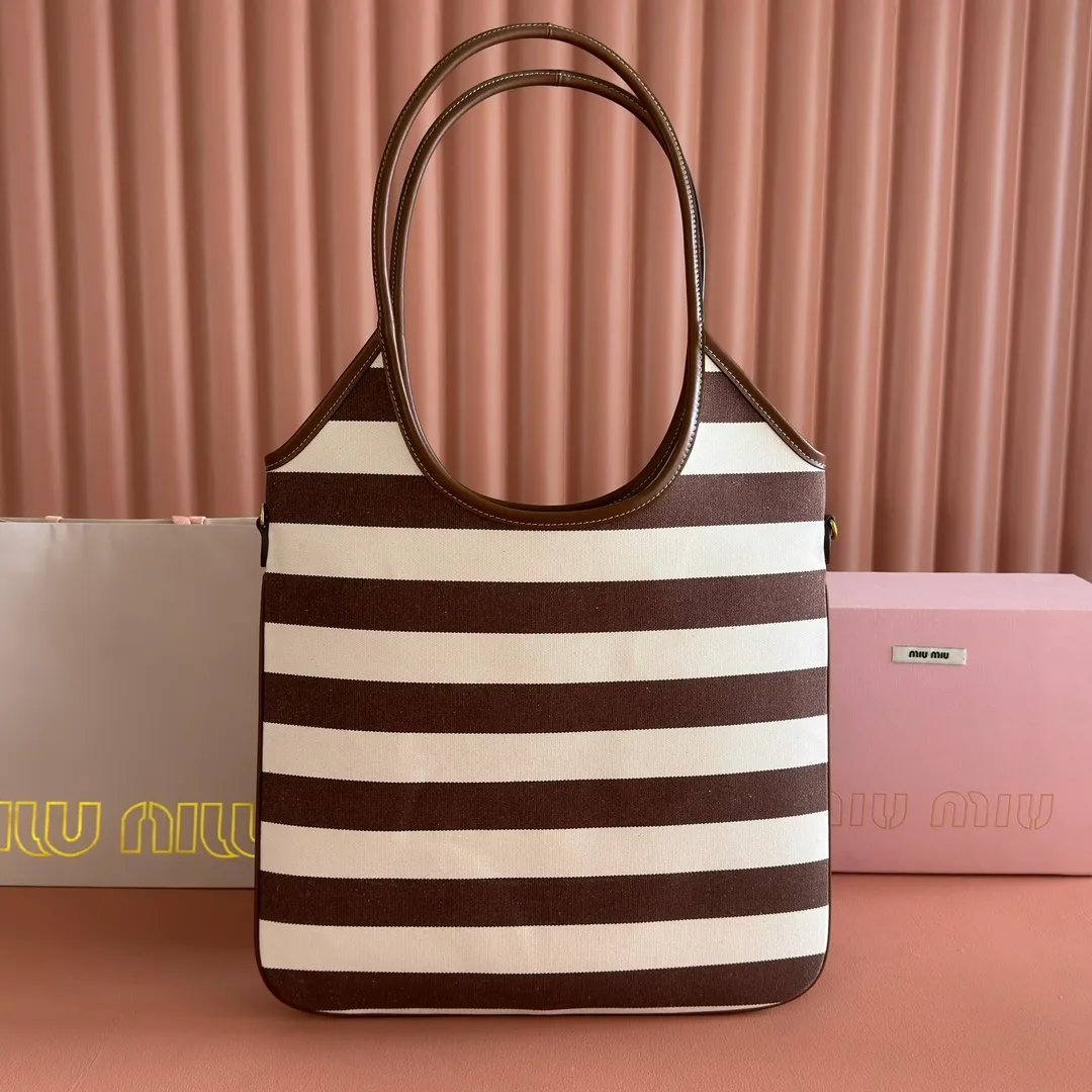 p1300. 💋💋💋【Full set of packages at the counter】𝗠𝗜𝗨𝗠𝗜𝗨 𝗙𝗪𝟮𝟱 𝗡𝗲𝘄 𝗮𝗿𝗿𝗶𝘃𝗮𝗹!      When striped canvas meets hobo's lazy gene, it grabs the first wave in autumn and winter. The relaxed feeling of commuting is directly capped. Classic blue and white nautical striped canvas × Italian calfskin piping. Flexible bag body hangs naturally. Tote capacity + Hobo's lazy feeling two-in-one. It looked like it was 𝗷𝗮𝗰𝗸𝗲𝘁 canvas, but when I touched the edge of the leather, I realized it was 𝗹𝘂𝘅𝘂𝗿𝘆!   The Ju Neng suit still hasn’t collapsed! 𝗵𝗼𝗯𝗼Bag shape looks slim 𝟭𝟬𝟬% 5BG231 stripes Size: 35×40cm