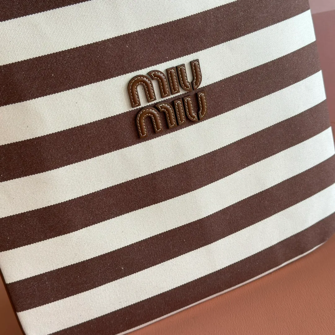 p1300. 💋💋💋【Full set of packages at the counter】𝗠𝗜𝗨𝗠𝗜𝗨 𝗙𝗪𝟮𝟱 𝗡𝗲𝘄 𝗮𝗿𝗿𝗶𝘃𝗮𝗹!      When striped canvas meets hobo's lazy gene, it grabs the first wave in autumn and winter. The relaxed feeling of commuting is directly capped. Classic blue and white nautical striped canvas × Italian calfskin piping. Flexible bag body hangs naturally. Tote capacity + Hobo's lazy feeling two-in-one. It looked like it was 𝗷𝗮𝗰𝗸𝗲𝘁 canvas, but when I touched the edge of the leather, I realized it was 𝗹𝘂𝘅𝘂𝗿𝘆!   The Ju Neng suit still hasn’t collapsed! 𝗵𝗼𝗯𝗼Bag shape looks slim 𝟭𝟬𝟬% 5BG231 stripes Size: 35×40cm