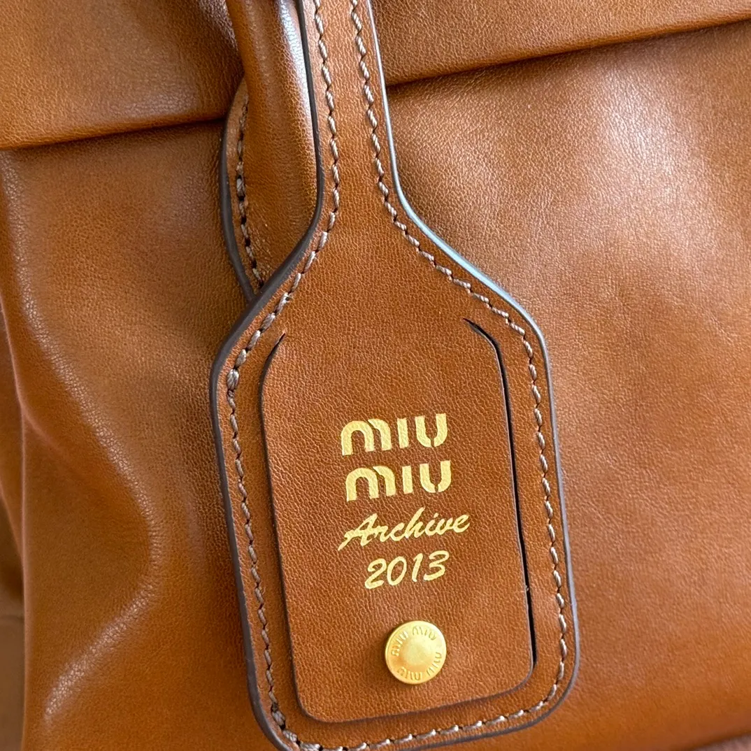 p1660💋💋💋【Configuring full counter package】Vintage cow leather Solitaire small handbag: 5BA301 Structured lines and exquisite details define this handbag, inspired by MiuMiu’s 2006 archives. An elegant style that combines classic and experimental is enhanced by the iconic logo on the front and a shiny finish. ·With handles ·Front and back pockets ·Golden hardware ·With zipper pocket and patch pockets ●Front lettering logo Width: 25cm, Height: 18cm, Length: 10cm?