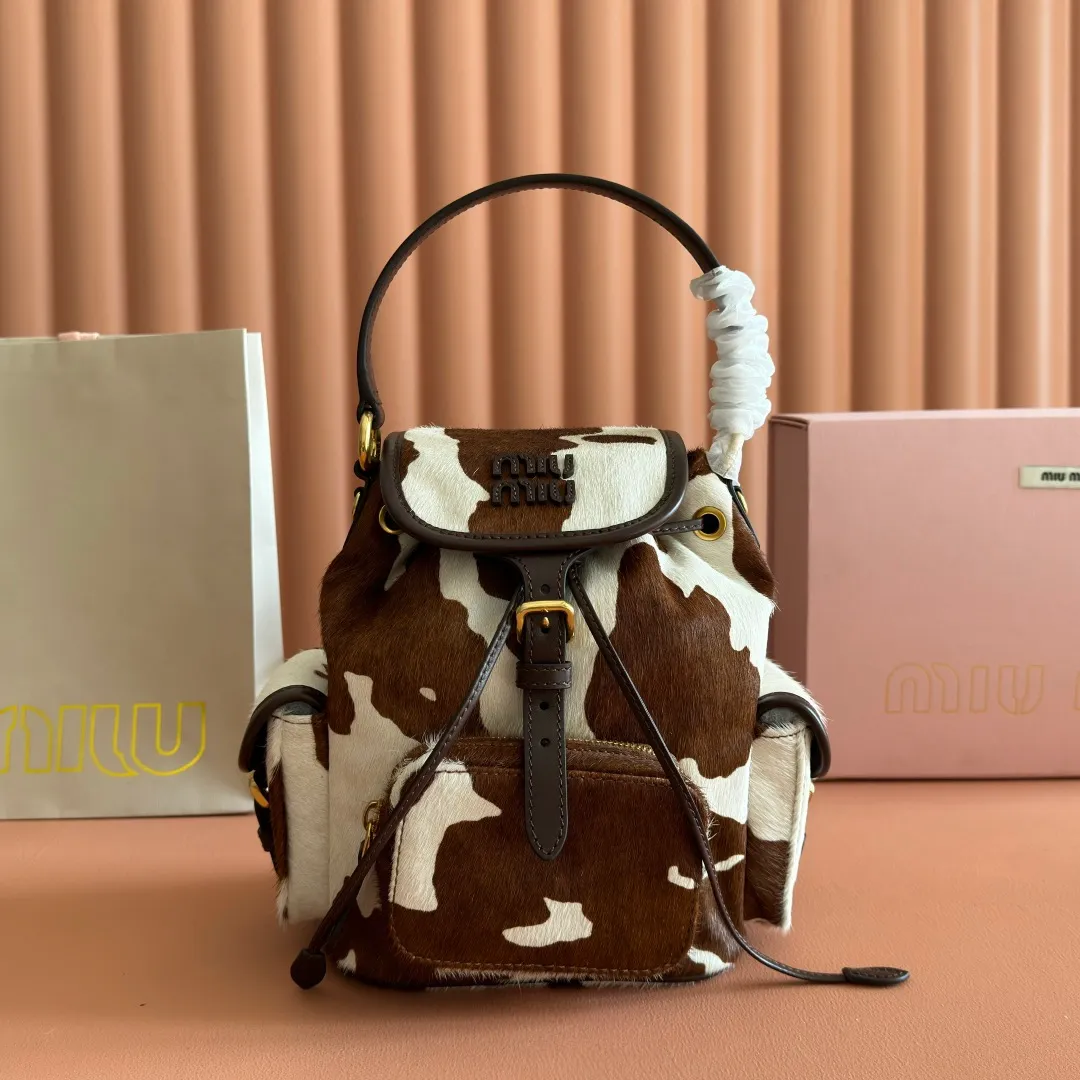 p1900💋💋💋【Original leather configuration counter complete package】𝐌𝐈𝐔𝐌𝐈𝐔 New cow pattern backpack Miu Miu's cow pattern backpack perfectly combines retro wildness and girly sweetness. The brown and white contrasting cow pattern fur material comes with an eye-catching buff, and is matched with the iconic logo embossing, showing the brand style in every detail; the drawstring flap design combines practicality with retro charm, and the combination of leather handles and shoulder straps, 🉑hand-held🉑shoulder-carrying, easily adapts to different wearing scenarios. Whether paired with casual denim or a sweet girl-style skirt, it can instantly inject a personal touch into the look and is the finishing touch to unlock niche fashion. Style number: 5B043 Small size: bottom length 23x height 25x width 13cm