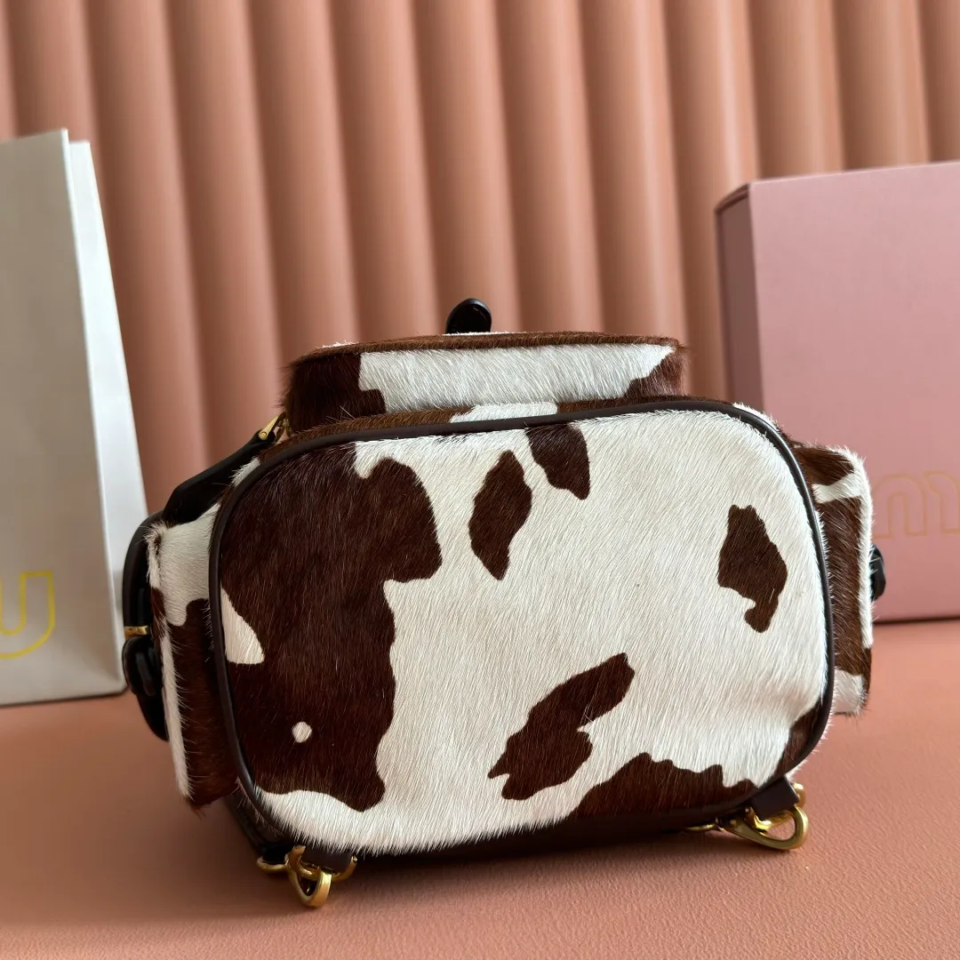 p1900💋💋💋【Original leather configuration counter complete package】𝐌𝐈𝐔𝐌𝐈𝐔 New cow pattern backpack Miu Miu's cow pattern backpack perfectly combines retro wildness and girly sweetness. The brown and white contrasting cow pattern fur material comes with an eye-catching buff, and is matched with the iconic logo embossing, showing the brand style in every detail; the drawstring flap design combines practicality with retro charm, and the combination of leather handles and shoulder straps, 🉑hand-held🉑shoulder-carrying, easily adapts to different wearing scenarios. Whether paired with casual denim or a sweet girl-style skirt, it can instantly inject a personal touch into the look and is the finishing touch to unlock niche fashion. Style number: 5B043 Small size: bottom length 23x height 25x width 13cm