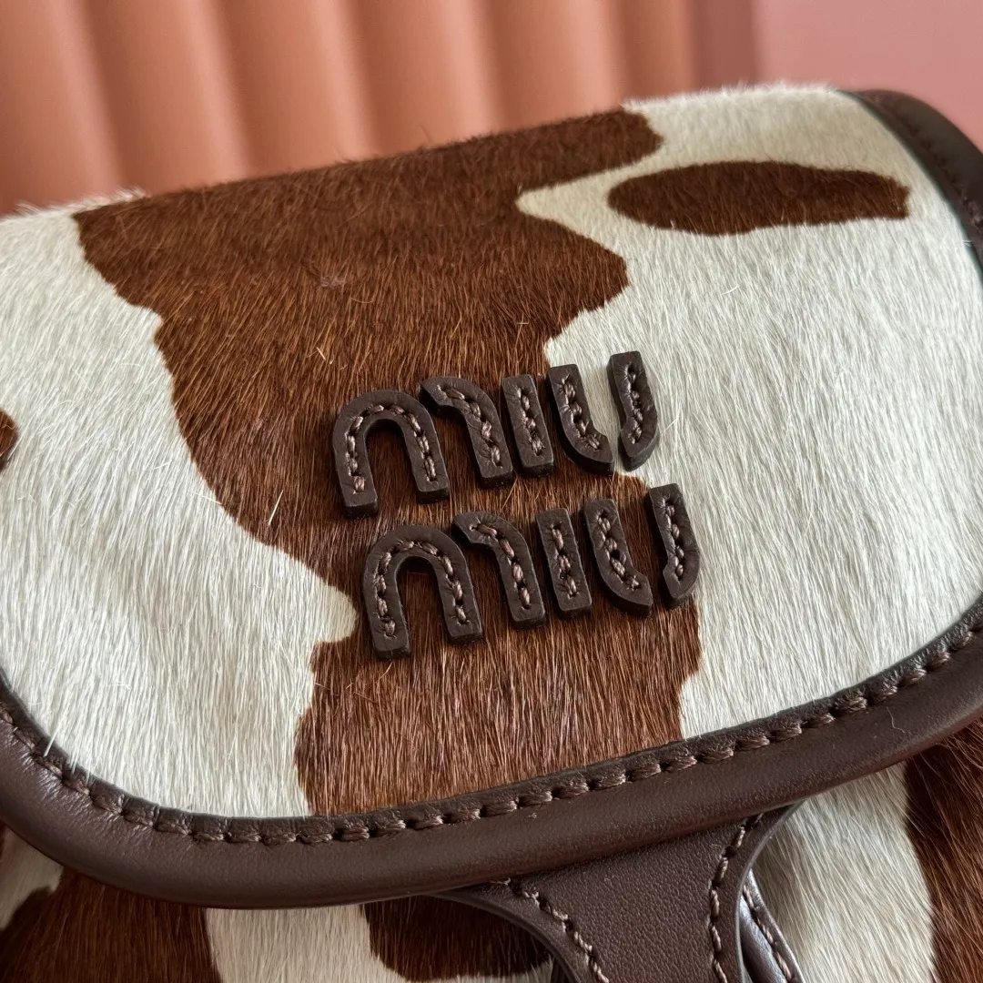 p1900💋💋💋【Original leather configuration counter complete package】𝐌𝐈𝐔𝐌𝐈𝐔 New cow pattern backpack Miu Miu's cow pattern backpack perfectly combines retro wildness and girly sweetness. The brown and white contrasting cow pattern fur material comes with an eye-catching buff, and is matched with the iconic logo embossing, showing the brand style in every detail; the drawstring flap design combines practicality with retro charm, and the combination of leather handles and shoulder straps, 🉑hand-held🉑shoulder-carrying, easily adapts to different wearing scenarios. Whether paired with casual denim or a sweet girl-style skirt, it can instantly inject a personal touch into the look and is the finishing touch to unlock niche fashion. Style number: 5B043 Small size: bottom length 23x height 25x width 13cm