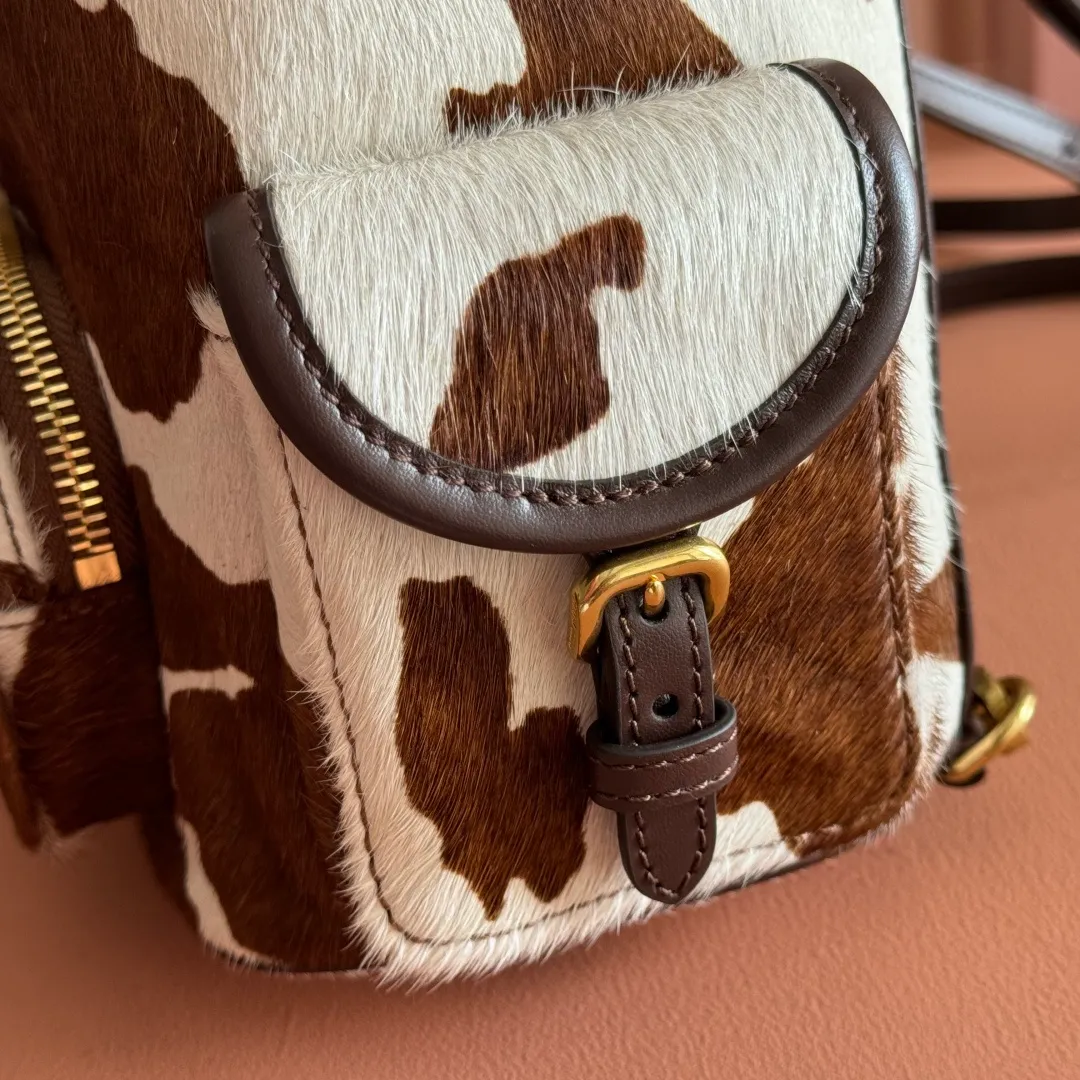 p1900💋💋💋【Original leather configuration counter complete package】𝐌𝐈𝐔𝐌𝐈𝐔 New cow pattern backpack Miu Miu's cow pattern backpack perfectly combines retro wildness and girly sweetness. The brown and white contrasting cow pattern fur material comes with an eye-catching buff, and is matched with the iconic logo embossing, showing the brand style in every detail; the drawstring flap design combines practicality with retro charm, and the combination of leather handles and shoulder straps, 🉑hand-held🉑shoulder-carrying, easily adapts to different wearing scenarios. Whether paired with casual denim or a sweet girl-style skirt, it can instantly inject a personal touch into the look and is the finishing touch to unlock niche fashion. Style number: 5B043 Small size: bottom length 23x height 25x width 13cm