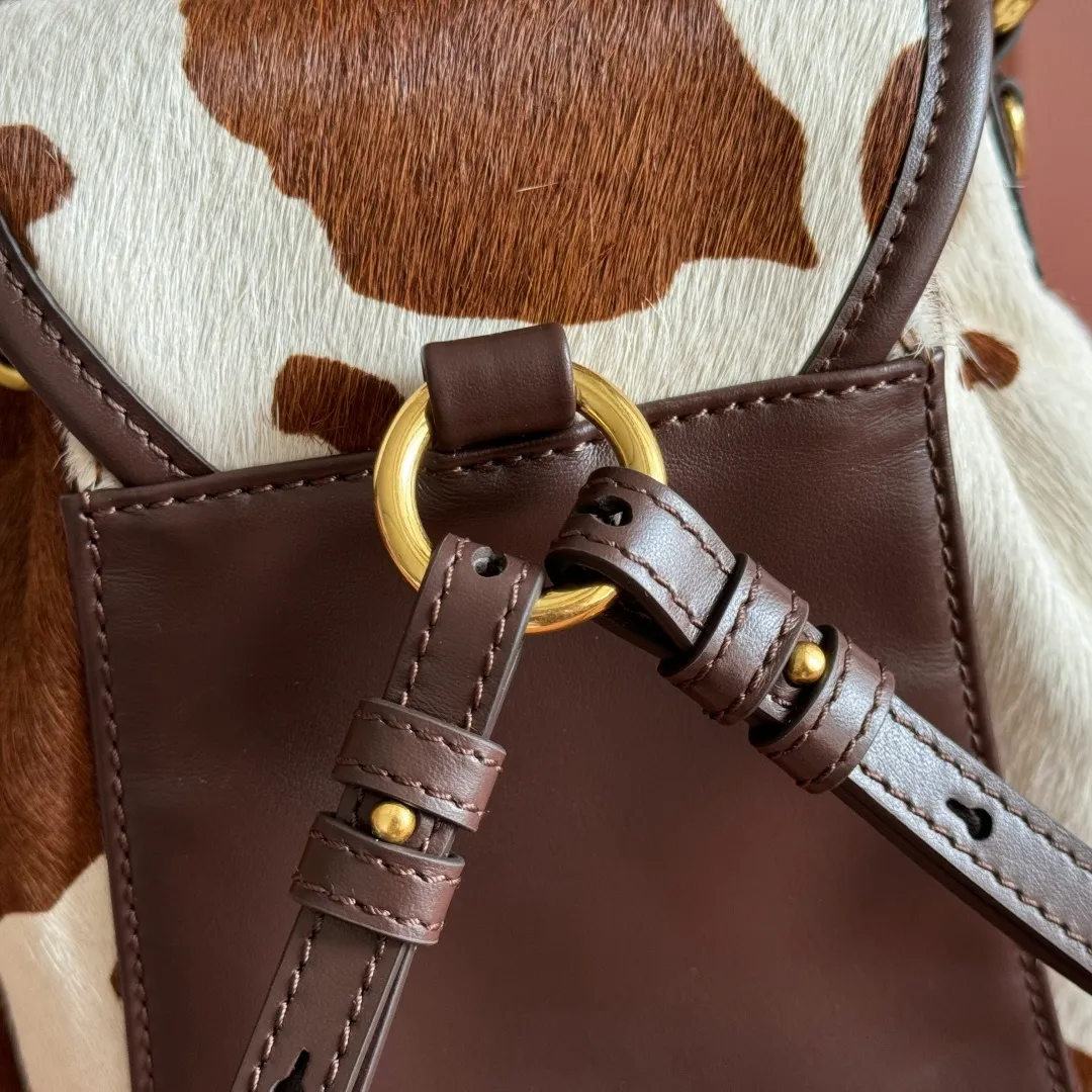 p1900💋💋💋【Original leather configuration counter complete package】𝐌𝐈𝐔𝐌𝐈𝐔 New cow pattern backpack Miu Miu's cow pattern backpack perfectly combines retro wildness and girly sweetness. The brown and white contrasting cow pattern fur material comes with an eye-catching buff, and is matched with the iconic logo embossing, showing the brand style in every detail; the drawstring flap design combines practicality with retro charm, and the combination of leather handles and shoulder straps, 🉑hand-held🉑shoulder-carrying, easily adapts to different wearing scenarios. Whether paired with casual denim or a sweet girl-style skirt, it can instantly inject a personal touch into the look and is the finishing touch to unlock niche fashion. Style number: 5B043 Small size: bottom length 23x height 25x width 13cm