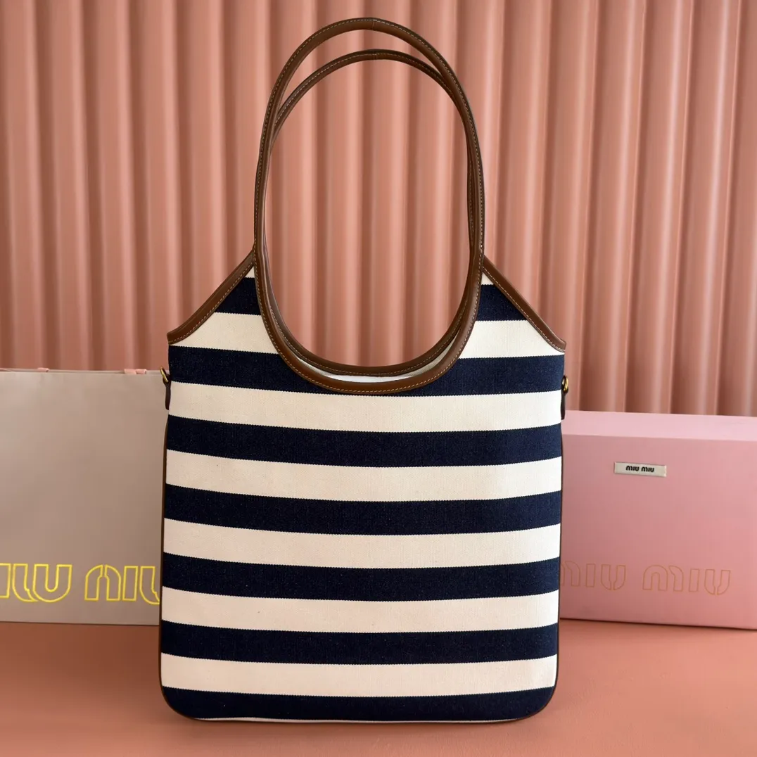 p1300. 💋💋💋【Full set of packages at the counter】𝗠𝗜𝗨𝗠𝗜𝗨 𝗙𝗪𝟮𝟱 𝗡𝗲𝘄 𝗮𝗿𝗿𝗶𝘃𝗮𝗹!      When striped canvas meets hobo's lazy gene, it grabs the first wave in autumn and winter. The relaxed feeling of commuting is directly capped. Classic blue and white nautical striped canvas × Italian calfskin piping. Flexible bag body hangs naturally. Tote capacity + Hobo's lazy feeling two-in-one. It looked like it was 𝗷𝗮𝗰𝗸𝗲𝘁 canvas, but when I touched the edge of the leather, I realized it was 𝗹𝘂𝘅𝘂𝗿𝘆!   The Ju Neng suit still hasn’t collapsed! 𝗵𝗼𝗯𝗼Bag shape looks slim 𝟭𝟬𝟬% 5BG231 stripes Size: 35×40cm