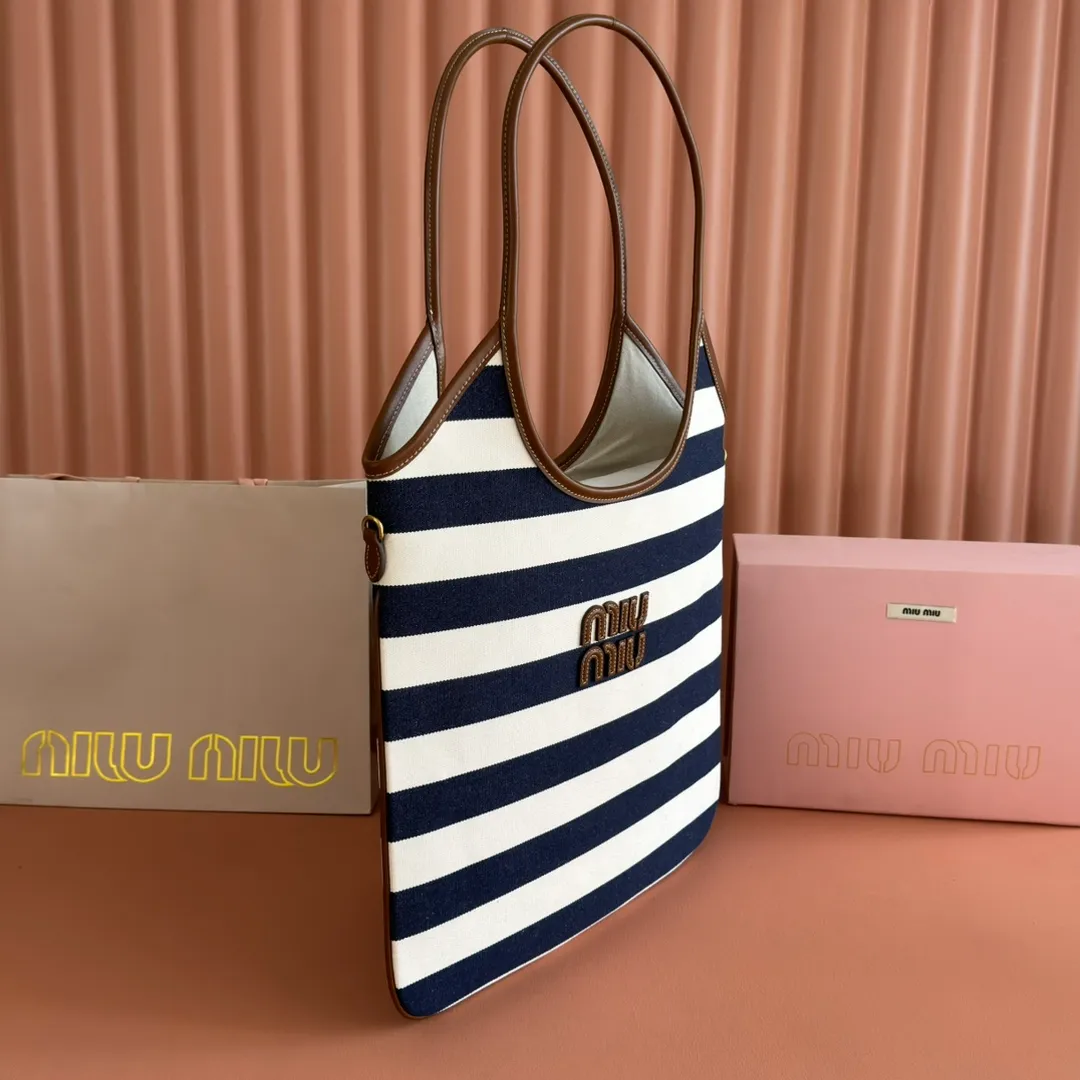 p1300. 💋💋💋【Full set of packages at the counter】𝗠𝗜𝗨𝗠𝗜𝗨 𝗙𝗪𝟮𝟱 𝗡𝗲𝘄 𝗮𝗿𝗿𝗶𝘃𝗮𝗹!      When striped canvas meets hobo's lazy gene, it grabs the first wave in autumn and winter. The relaxed feeling of commuting is directly capped. Classic blue and white nautical striped canvas × Italian calfskin piping. Flexible bag body hangs naturally. Tote capacity + Hobo's lazy feeling two-in-one. It looked like it was 𝗷𝗮𝗰𝗸𝗲𝘁 canvas, but when I touched the edge of the leather, I realized it was 𝗹𝘂𝘅𝘂𝗿𝘆!   The Ju Neng suit still hasn’t collapsed! 𝗵𝗼𝗯𝗼Bag shape looks slim 𝟭𝟬𝟬% 5BG231 stripes Size: 35×40cm