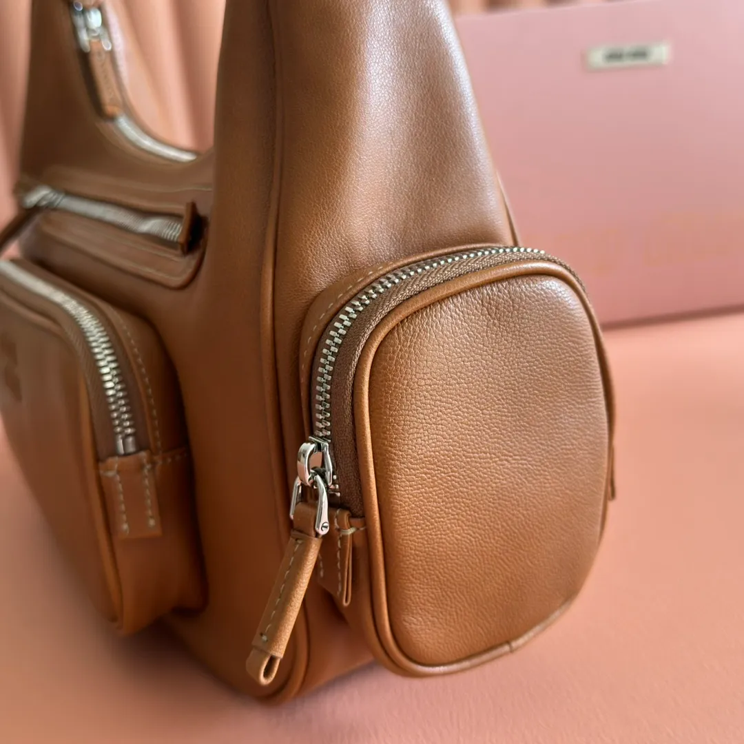 p2200💋💋💋【Full set of packaging at the counter】𝗠𝗶𝘂 𝗠𝗶𝘂 𝗣𝗼𝗰𝗸𝗲𝘁Motorcycle bag This MIU pocket bag is so big that even a rich family’s daughter is carrying it! Full leather inside and out, the leather is very soft and feels super good. The Tori zipper + three-dimensional pockets are retro and can be carried in one bag under the arm to unlock two ways of carrying it. Fashionable girls, please plant this motorcycle bag! Size: 38cm long (measured including the 2 side pockets, 33cm excluding it) Style number: 5BC189 caramel color Dimensions: length 38×width 14×height 20cm