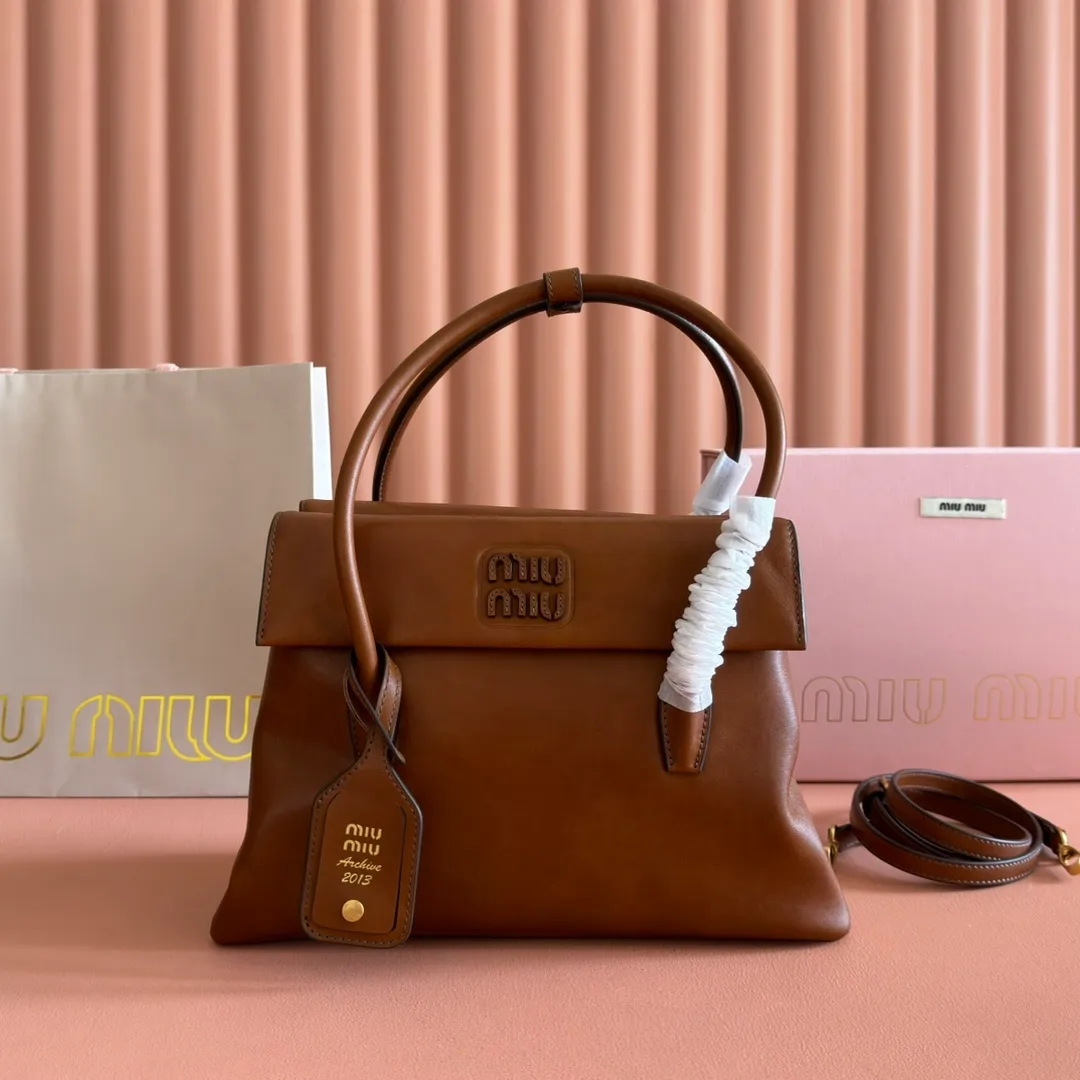 p1700💋💋💋【Configuring full counter package】Vintage cow leather Solitaire medium handbag: 5BA302 Structured lines and exquisite details define this handbag, inspired by MiuMiu's 2006 archives. An elegant style that combines classic and experimental is enhanced by the iconic logo on the front and a shiny finish. ·With handle ●With removable decoration. Comes with sliding and removable shoulder strap. Minimum length: 110 cm - Maximum length: 120 cm - Minimum drop: 50 cm - Maximum drop: 55 cm · Front and back pockets · Gold hardware · Zippered pockets and patch pockets ● Lettering logo on the front Width: 28 cm, Height: 19.5 cm, Length: 11 cm