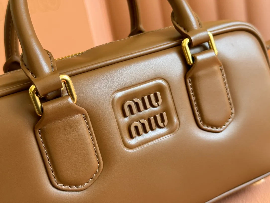 p1640💋💋💋【Full set of packaging at the counter】MIU MIU Miu Miu Caramel Bowling Upper Body Effect! Miu Miu Women's Arcadia Cowhide Handbag Crossbody Bag👝Lightly padded design makes the handbag look fuller, showing a cosmopolitan style. The letter logo, which echoes the finish of the metal hardware, straddles the line between function and decoration, giving this handbag a unique aesthetic and classic feel. Size: 22✖️10.5✖️7.5cm Style number: 5bb142 brown