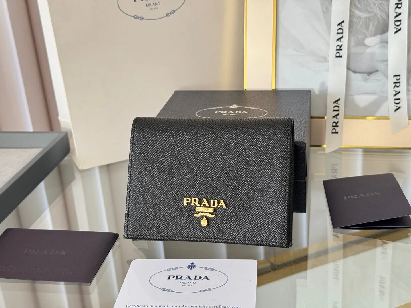 Prada women's two-fold short clip, with coin pocket and coin pocket. Model 1M0204, cross-grain cowhide. Size: 11.2x9.5cm. Simple and practical to enhance personal taste.