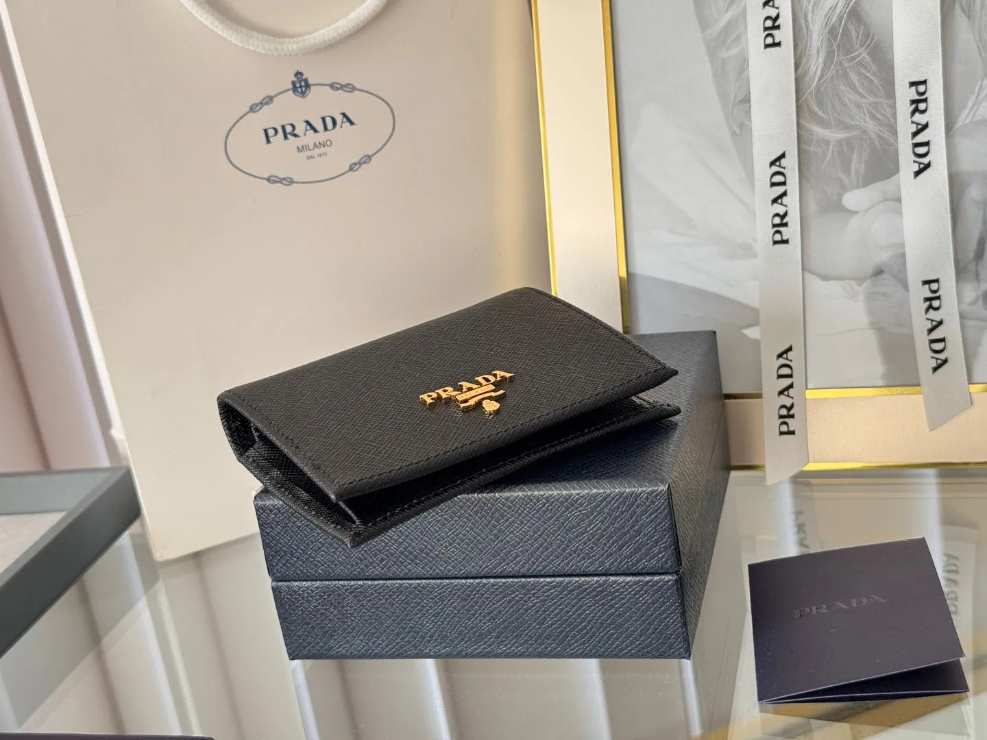Prada women's two-fold short clip, with coin pocket and coin pocket. Model 1M0204, cross-grain cowhide. Size: 11.2x9.5cm. Simple and practical to enhance personal taste.