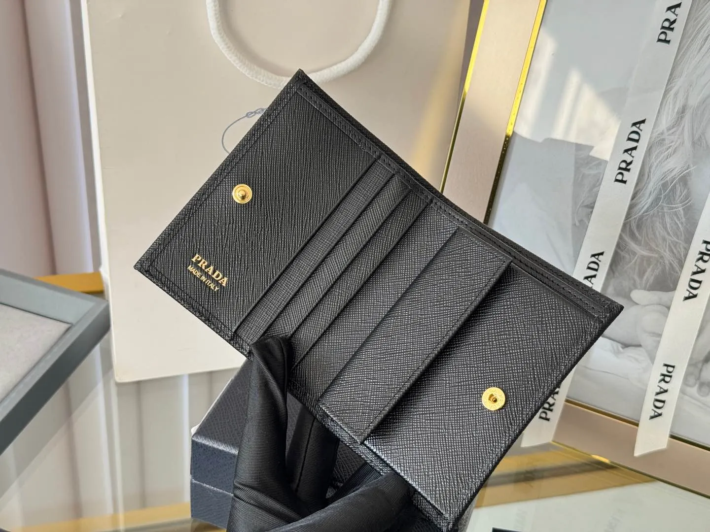 Prada women's two-fold short clip, with coin pocket and coin pocket. Model 1M0204, cross-grain cowhide. Size: 11.2x9.5cm. Simple and practical to enhance personal taste.