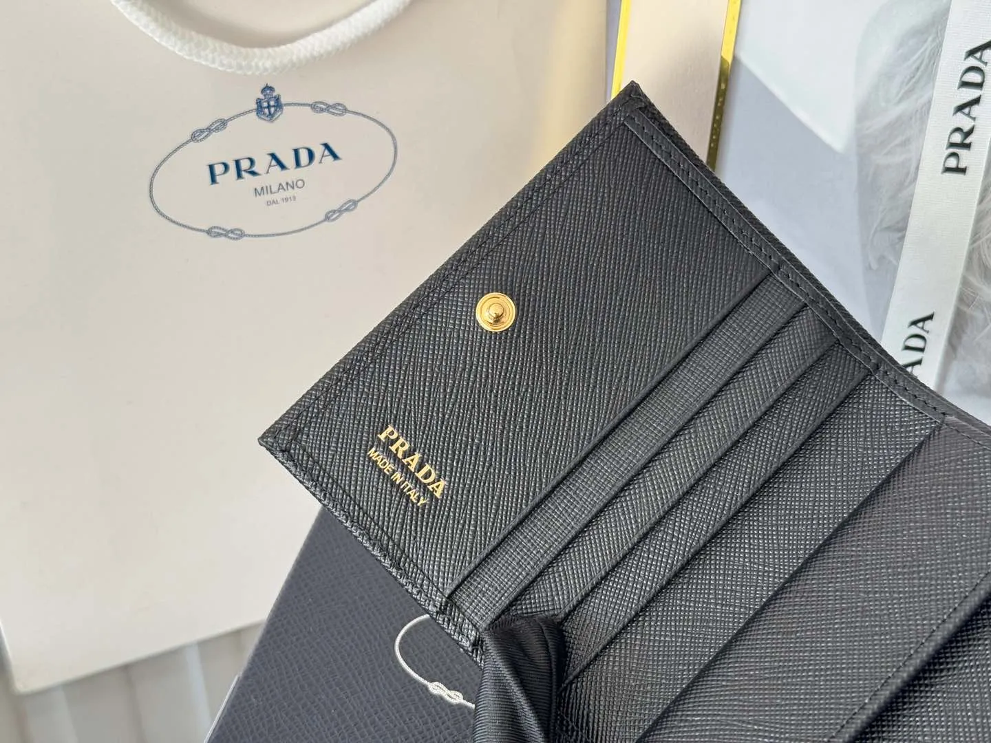 Prada women's two-fold short clip, with coin pocket and coin pocket. Model 1M0204, cross-grain cowhide. Size: 11.2x9.5cm. Simple and practical to enhance personal taste.