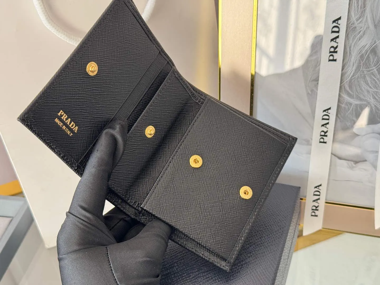 Prada women's two-fold short clip, with coin pocket and coin pocket. Model 1M0204, cross-grain cowhide. Size: 11.2x9.5cm. Simple and practical to enhance personal taste.