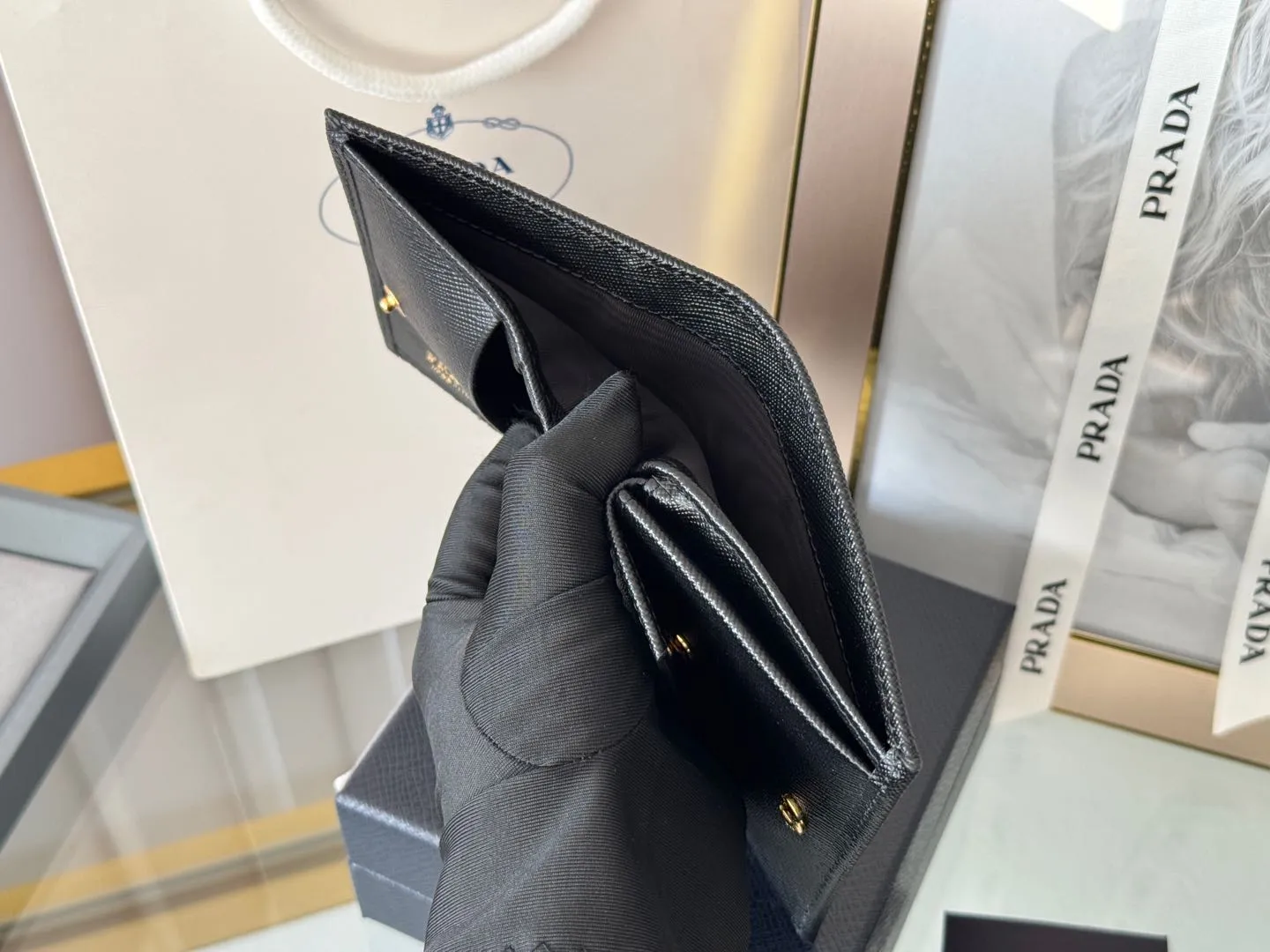 Prada women's two-fold short clip, with coin pocket and coin pocket. Model 1M0204, cross-grain cowhide. Size: 11.2x9.5cm. Simple and practical to enhance personal taste.