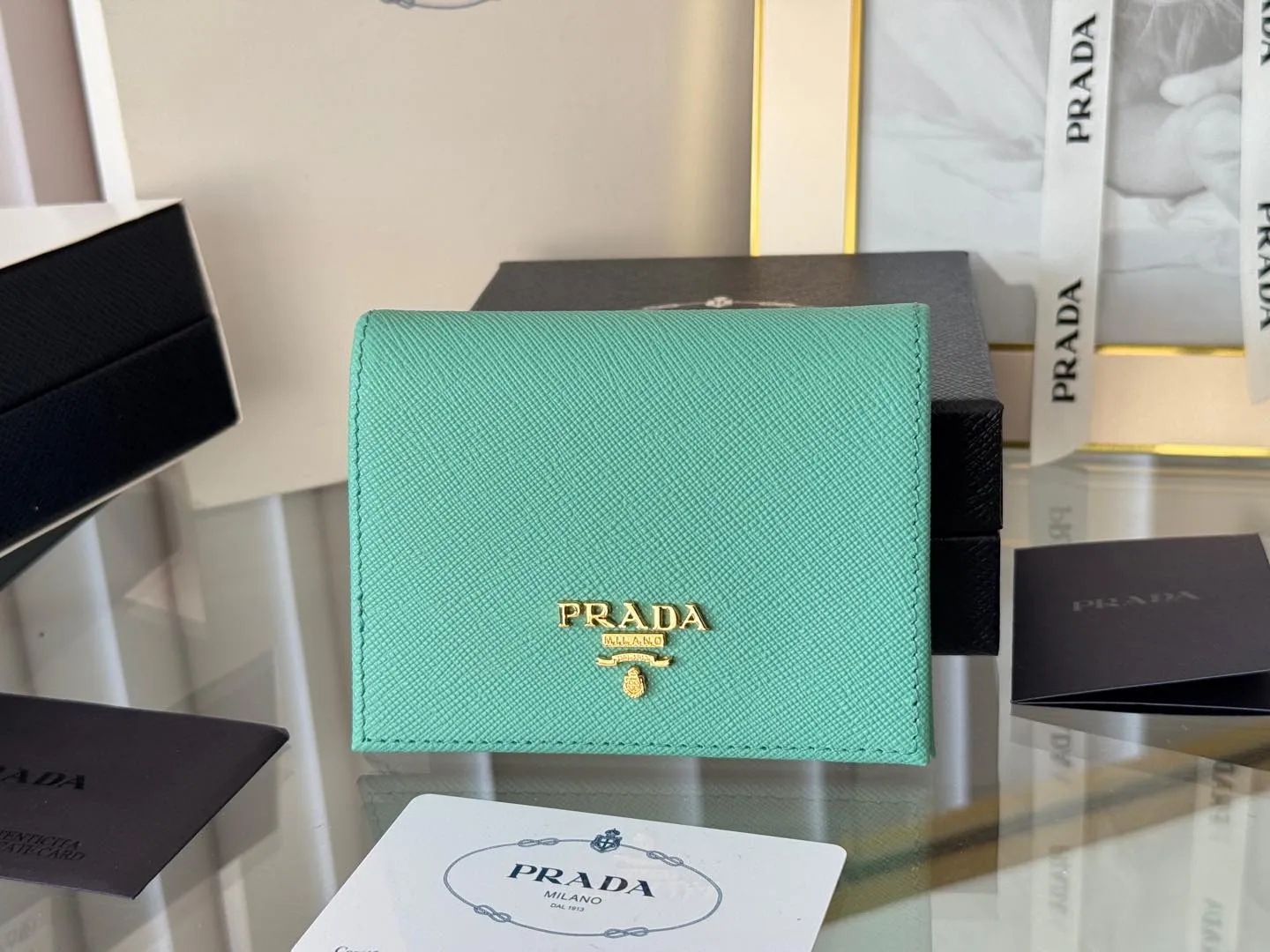 Prada women's two-fold short clip, with coin pocket and coin pocket. Model 1M0204, cross-grain cowhide. Size: 11.2x9.5cm. Simple and practical to enhance personal taste.