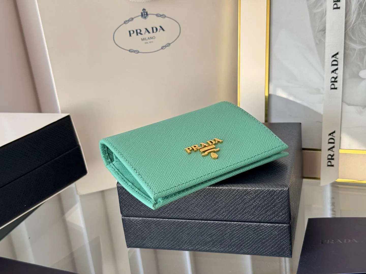 Prada women's two-fold short clip, with coin pocket and coin pocket. Model 1M0204, cross-grain cowhide. Size: 11.2x9.5cm. Simple and practical to enhance personal taste.