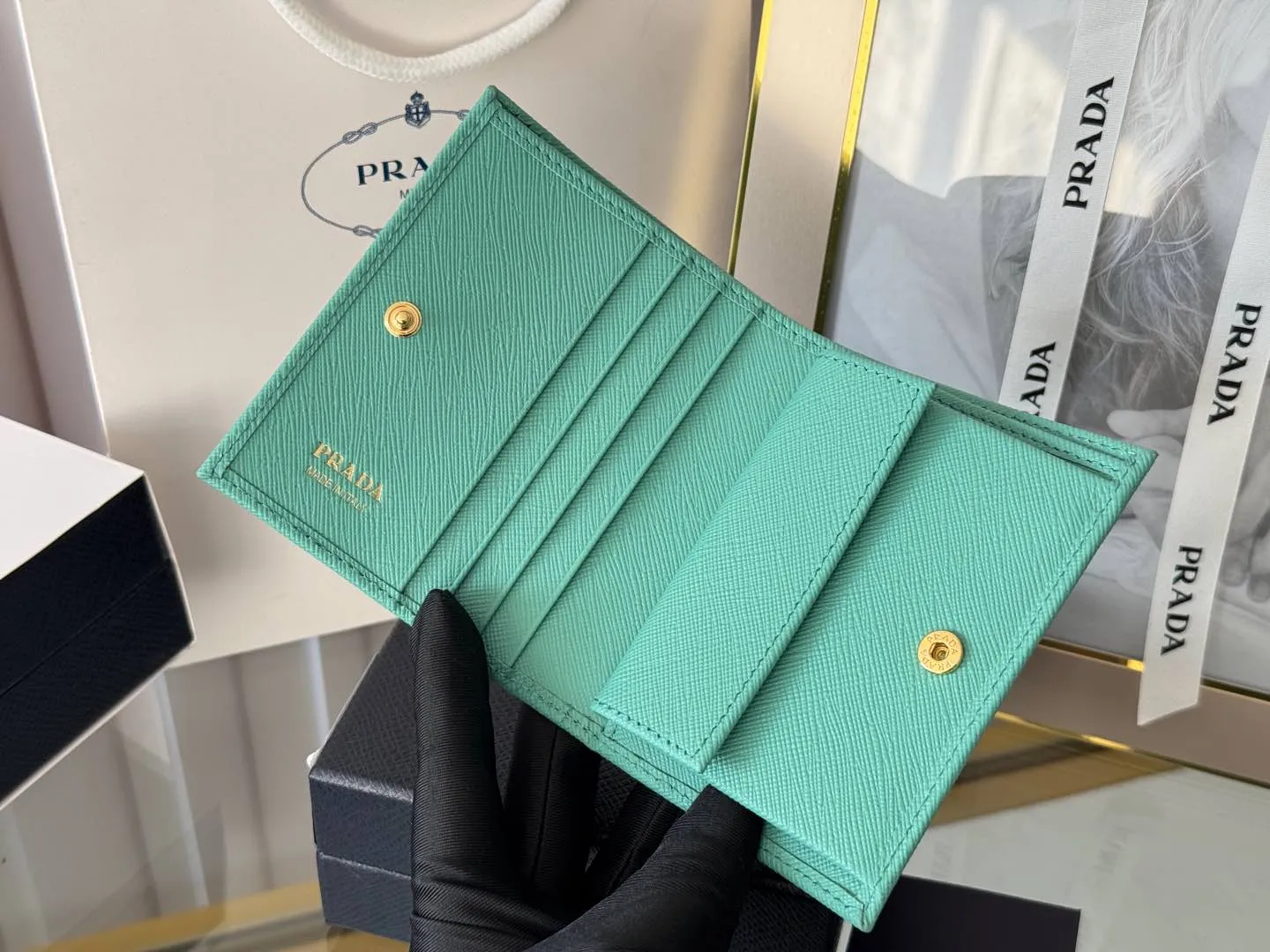 Prada women's two-fold short clip, with coin pocket and coin pocket. Model 1M0204, cross-grain cowhide. Size: 11.2x9.5cm. Simple and practical to enhance personal taste.