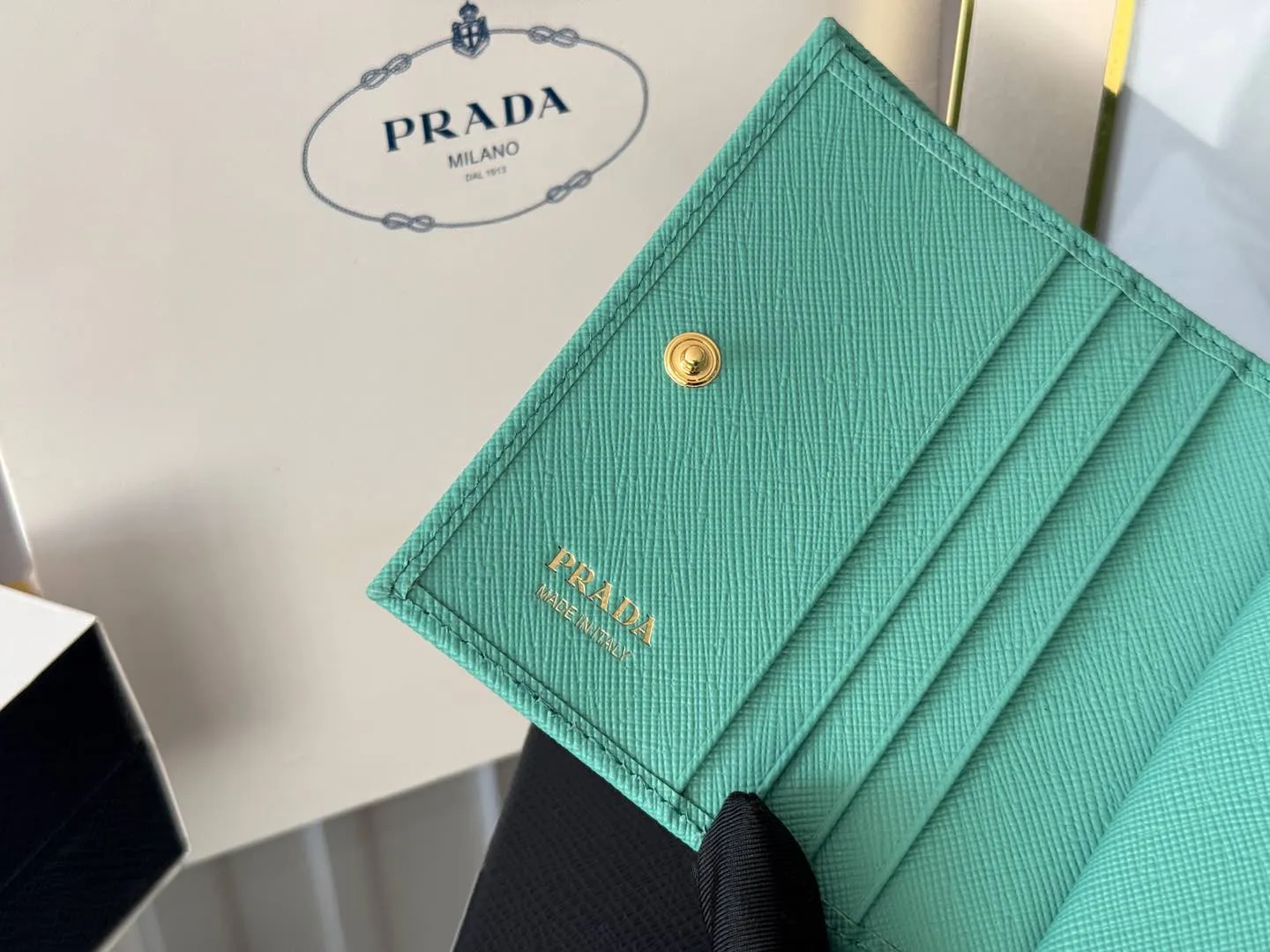 Prada women's two-fold short clip, with coin pocket and coin pocket. Model 1M0204, cross-grain cowhide. Size: 11.2x9.5cm. Simple and practical to enhance personal taste.