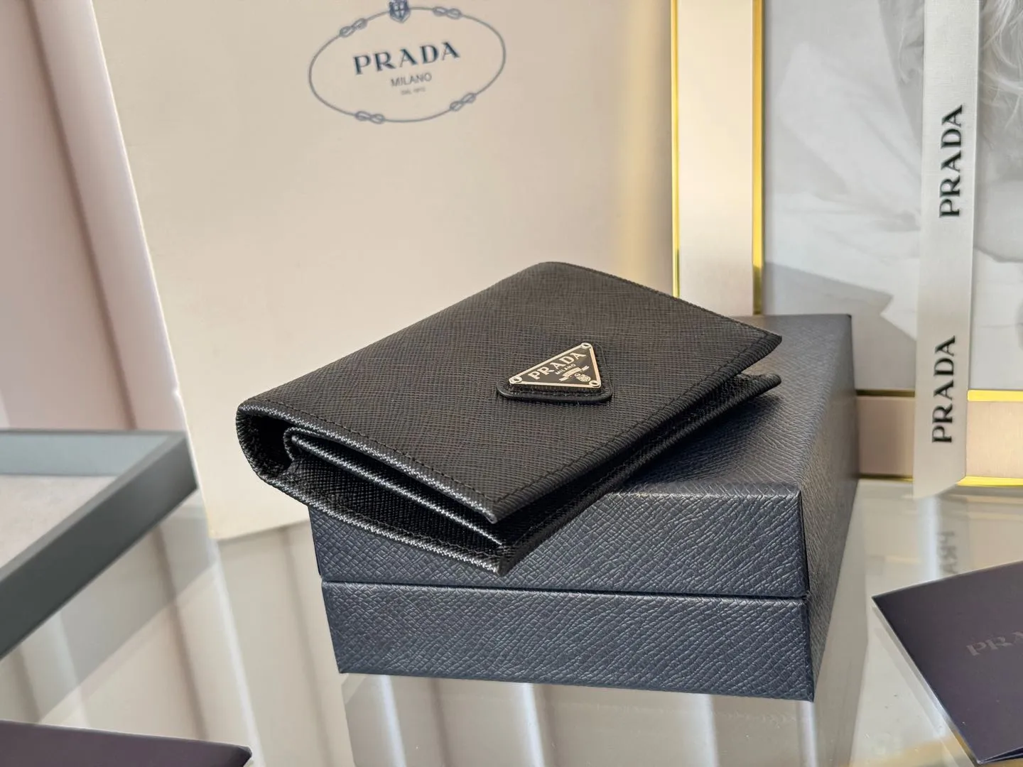 Prada women's two-fold short clip, with coin pocket and coin pocket. Model 1M0204, cross-grain cowhide. Size: 11.2x9.5cm. Simple and practical to enhance personal taste.