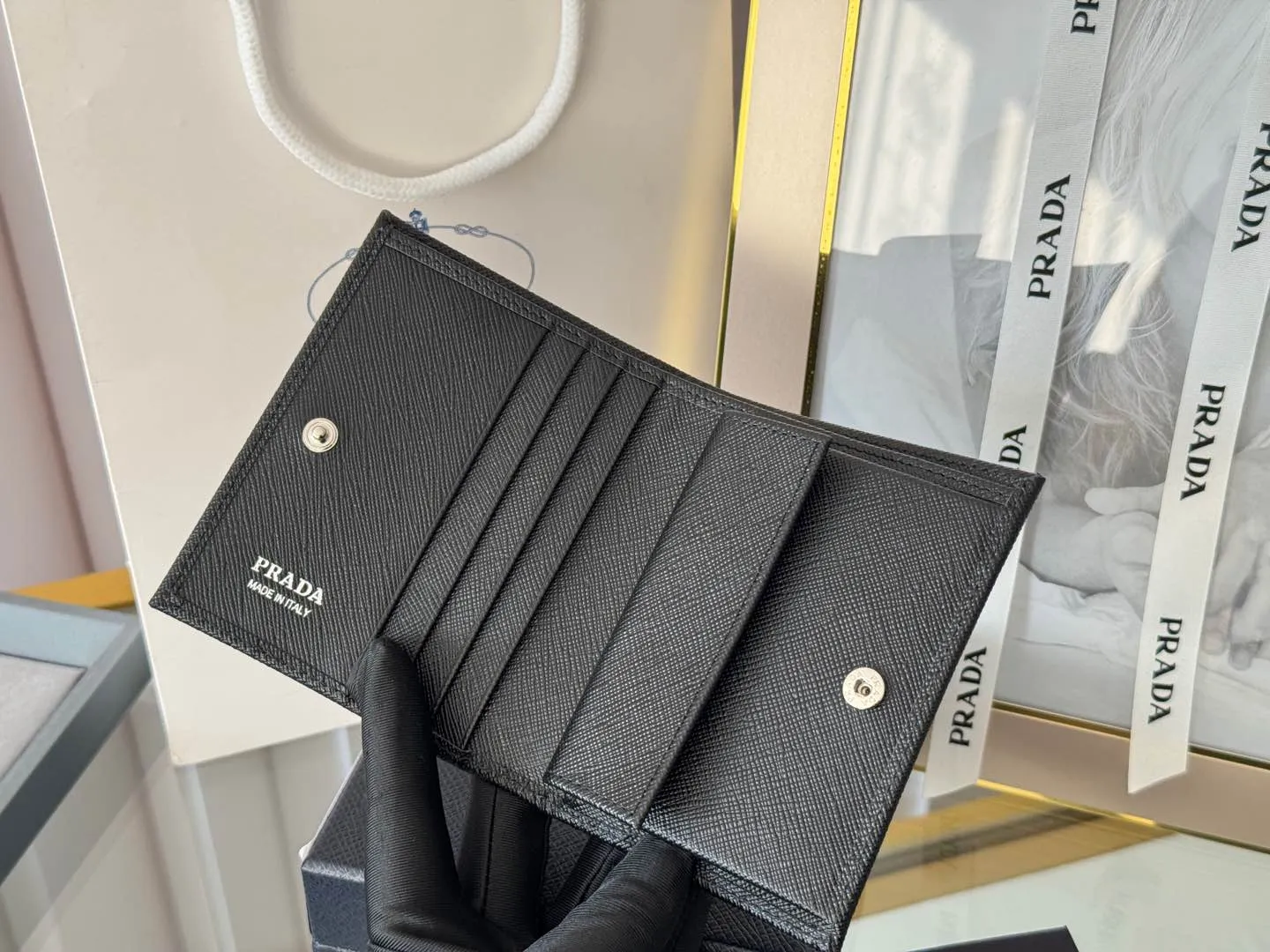 Prada women's two-fold short clip, with coin pocket and coin pocket. Model 1M0204, cross-grain cowhide. Size: 11.2x9.5cm. Simple and practical to enhance personal taste.