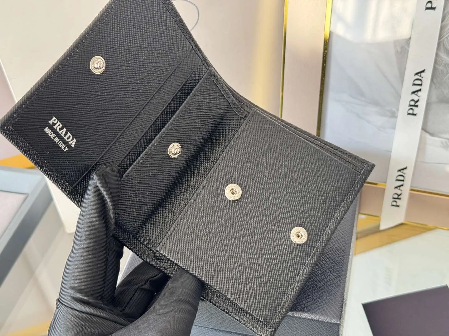 Prada women's two-fold short clip, with coin pocket and coin pocket. Model 1M0204, cross-grain cowhide. Size: 11.2x9.5cm. Simple and practical to enhance personal taste.