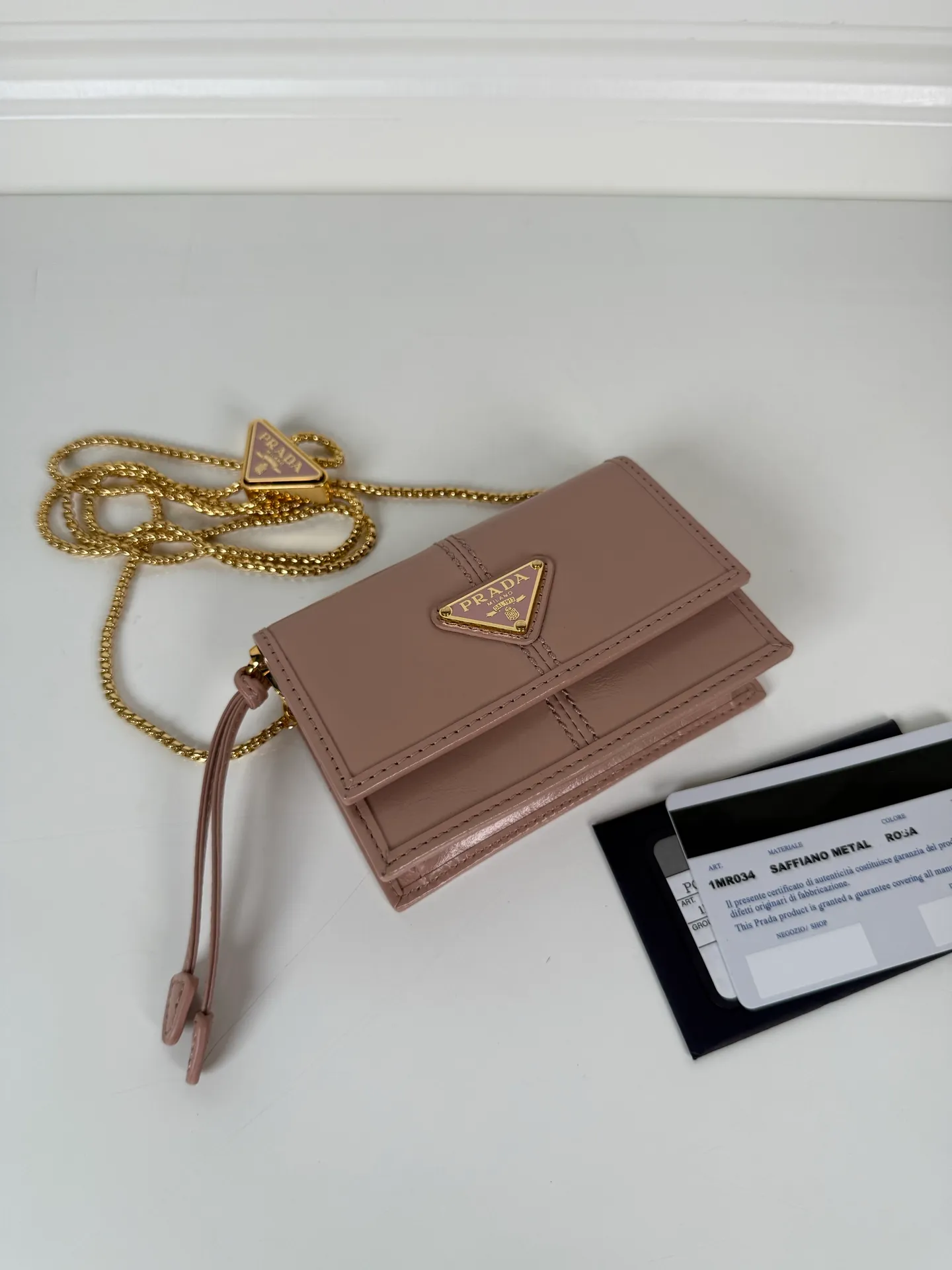 💰900; P Home ➡️Multifunctional mini backpack for women, model 1MR034, flip-top card holder with detachable Saffiano leather shoulder strap, metal triangular micro-mark decorating the front, size 11.5 x8 x2.5cm, two card slots inside, snap closure, in summer it is a mini backpack, in winter it can be turned into a small card holder by removing the shoulder strap, super practical and worth owning👍