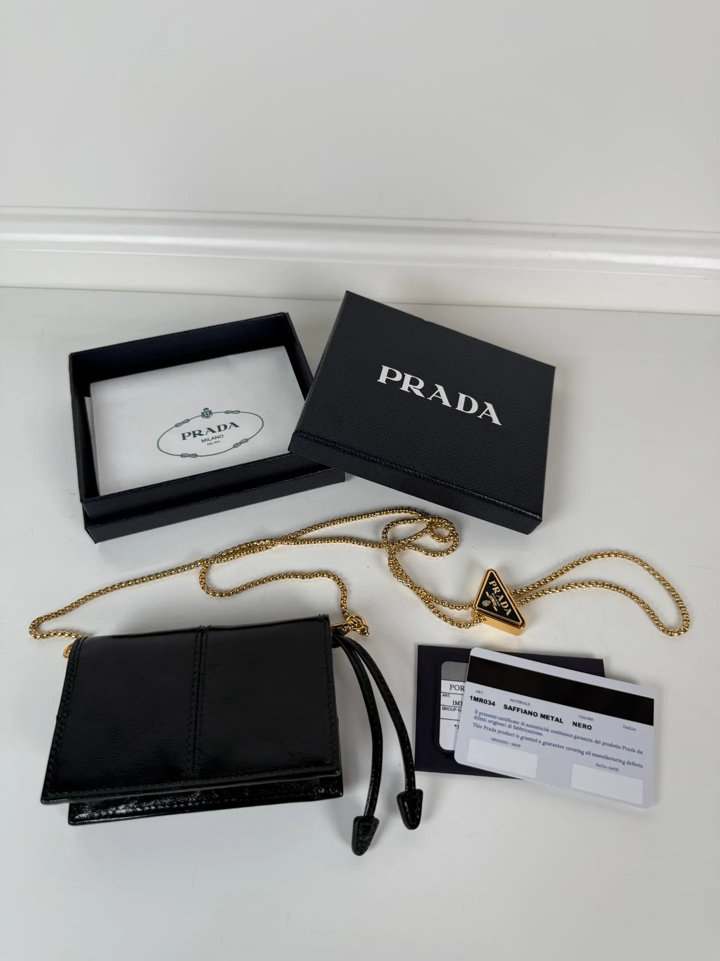 P Home➡️Ladies multifunctional mini backpack, model 1MR034, flip-top card holder with detachable Saffiano leather shoulder strap, metal triangular micro logo decorating the front, size 11.5 x8 x2.5cm, two card slots inside, snap closure, it is a mini backpack in summer, and it can be transformed into a small card holder by removing the shoulder strap in winter. It is super practical and worth having👍