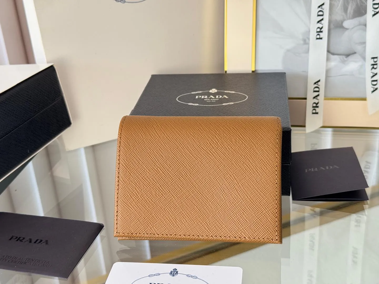 Prada women's two-fold short clip, with coin pocket and coin pocket. Model 1M0204, cross-grain cowhide. Size: 11.2x9.5cm. Simple and practical to enhance personal taste.